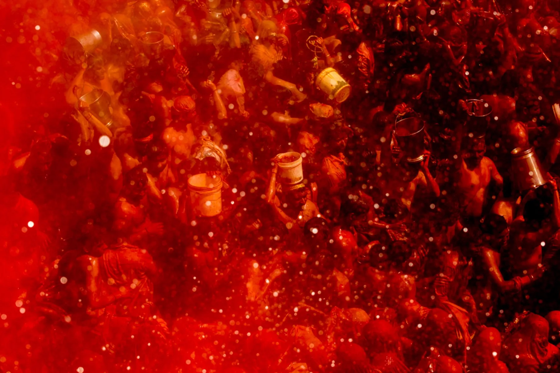 Blick von oben auf Menschen in einer Wolke roten Pulvers beim Holi-Fest.