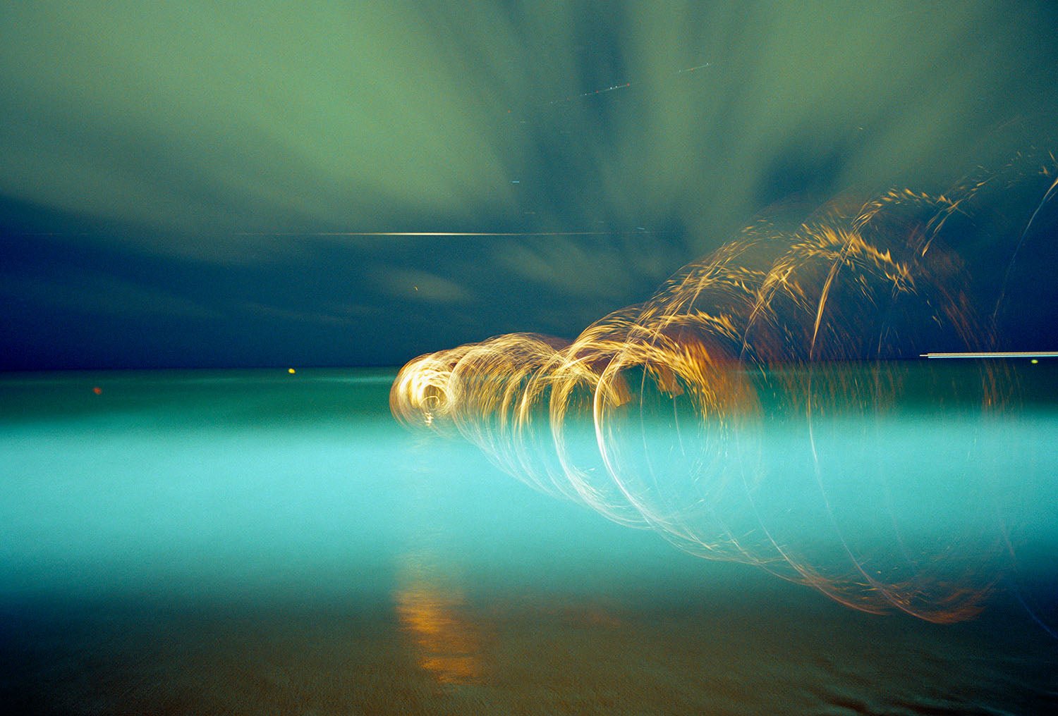 Photographie d’art d’André Wagner: Des boucles de lumière dorée traversent une surface d’eau turquoise et s’ouvrent vers la droite en arcs fins — BLUE LAGUNA, Spanien.