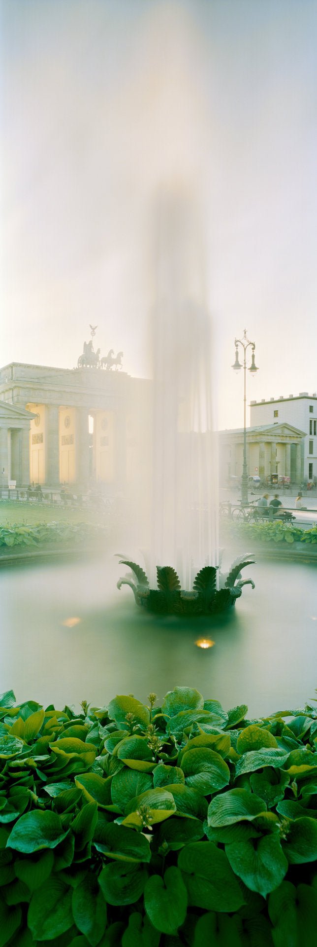 Fine art photography by André Wagner: A bright column of water rises through the exceptionally narrow frame — Brandenburger Tor, Deutschland.