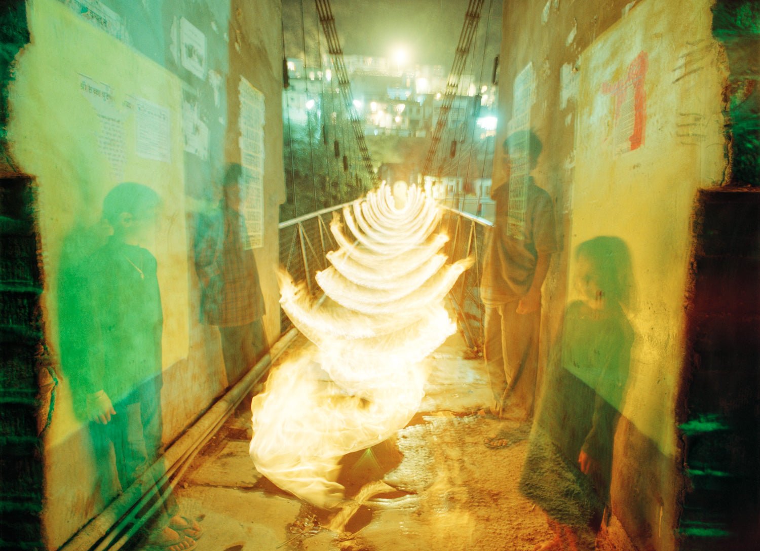 Fine art photography by André Wagner: Bright golden arcs repeat along a narrow passage, leading towards a smaller light zone in the distance — Channeling, Indien.