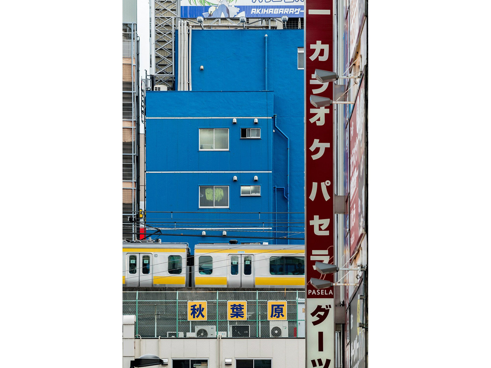 Fine art photography by André Wagner: A strong blue wall dominates the narrow vertical format — Cityscape tokyo 1, Japan.