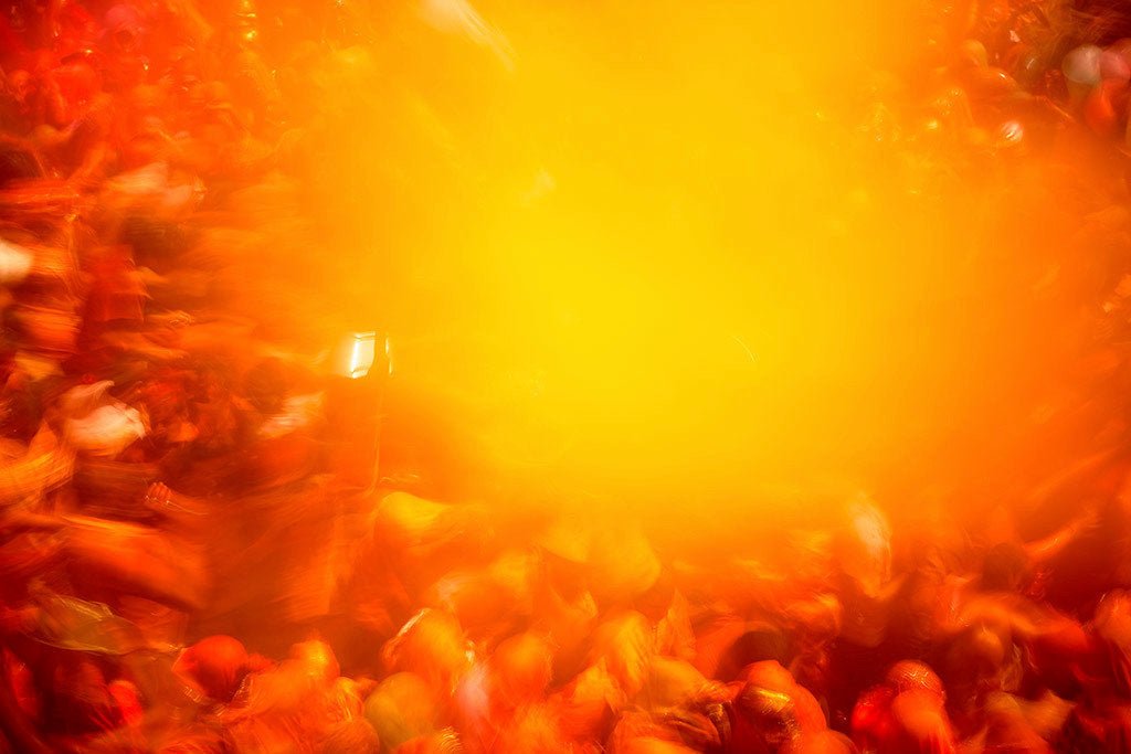 Photographie d’art d’André Wagner: Une foule dense entoure un grand nuage jaune et orangé — Color Bomb, Indien.