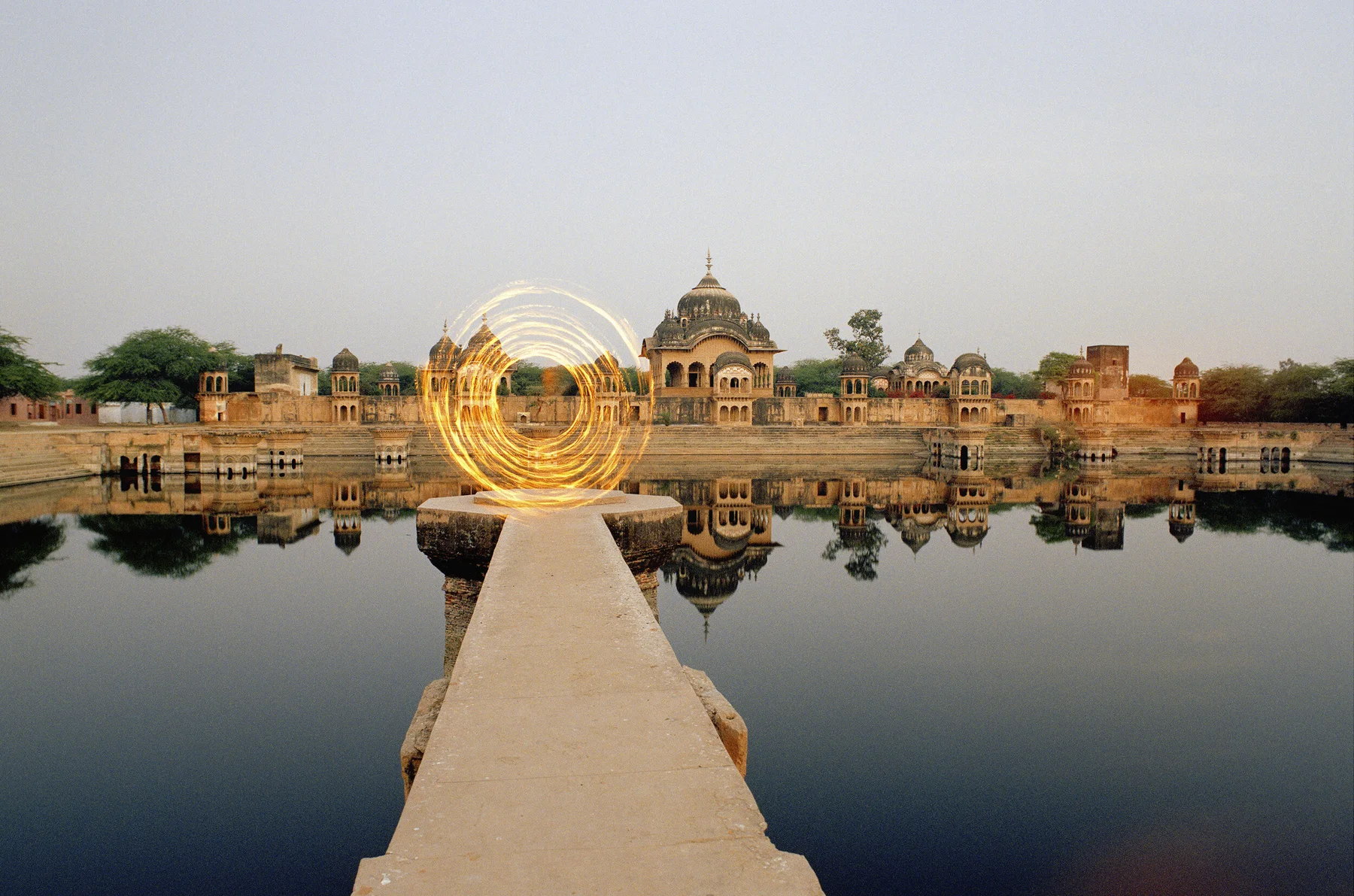 Fine art photography by André Wagner: A narrow pale walkway leads from the centre towards a golden circle of light — Dimension door, Indien.