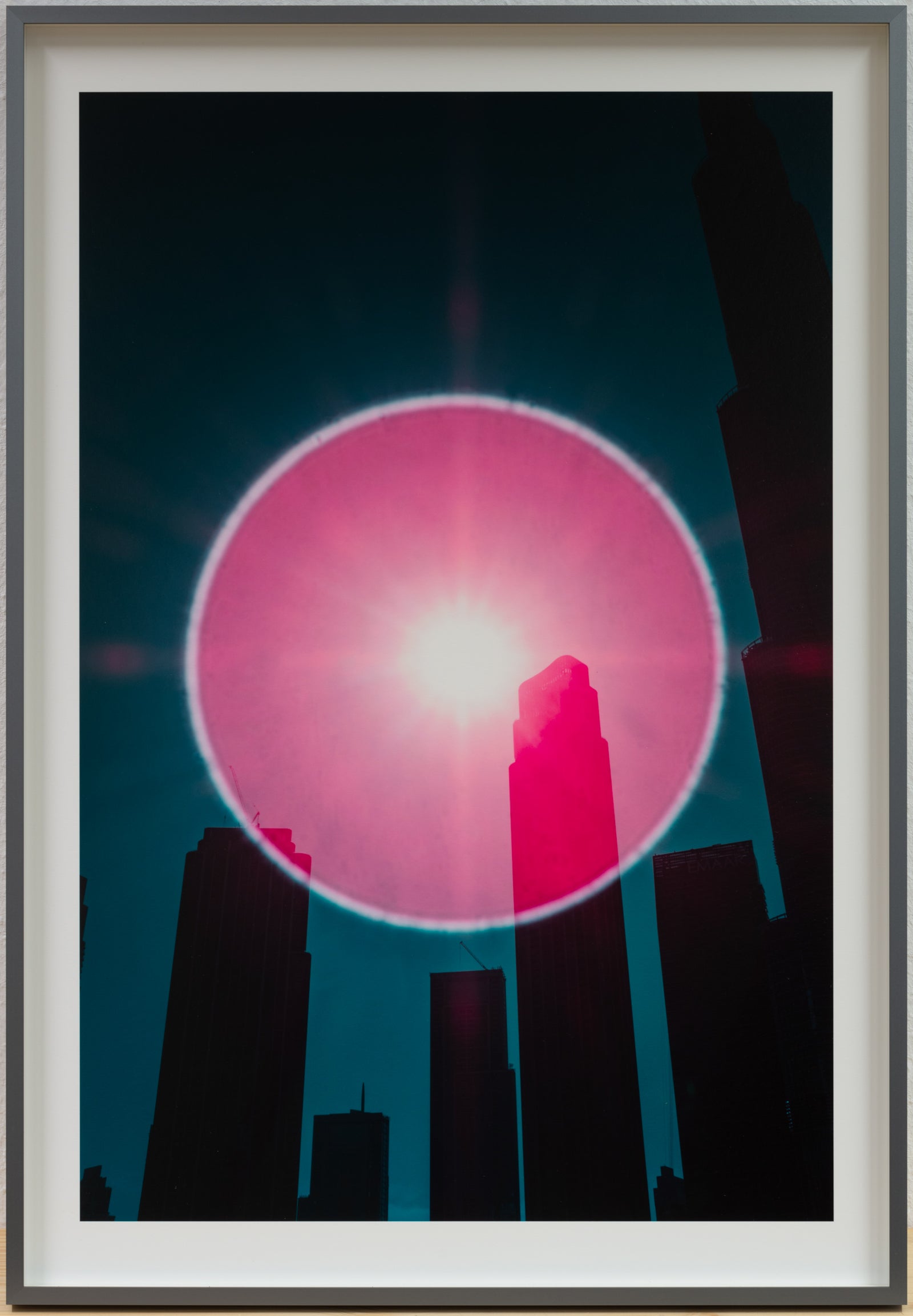 Photographie d’art infrarouge d’André Wagner: Un grand cercle de lumière rosée flotte au-dessus de silhouettes de bâtiments sombres et élancées — Dubai in the eye of the cosmic observer, Vereinigte arabische emirate 2.