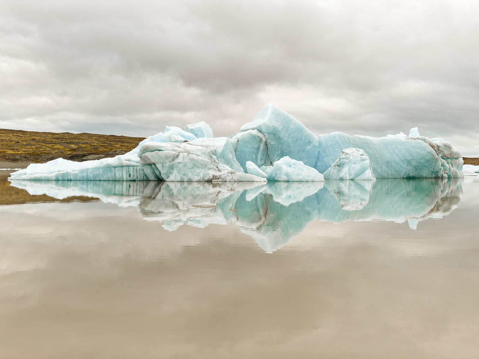 Photographie d’art d’André Wagner: Des masses de glace claires aux reflets bleutés reposent dans une eau presque lisse — Earthporn 2, Island.