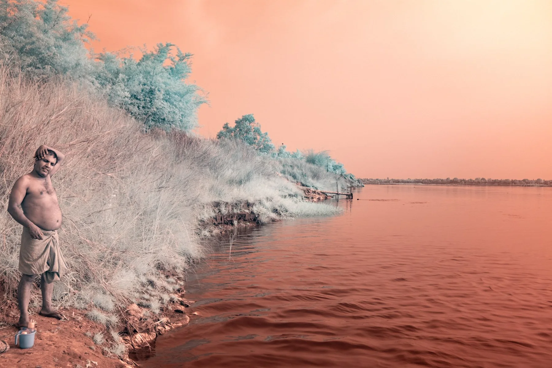 Un homme sur la rive d&rsquo;une rivi&egrave;re orange.