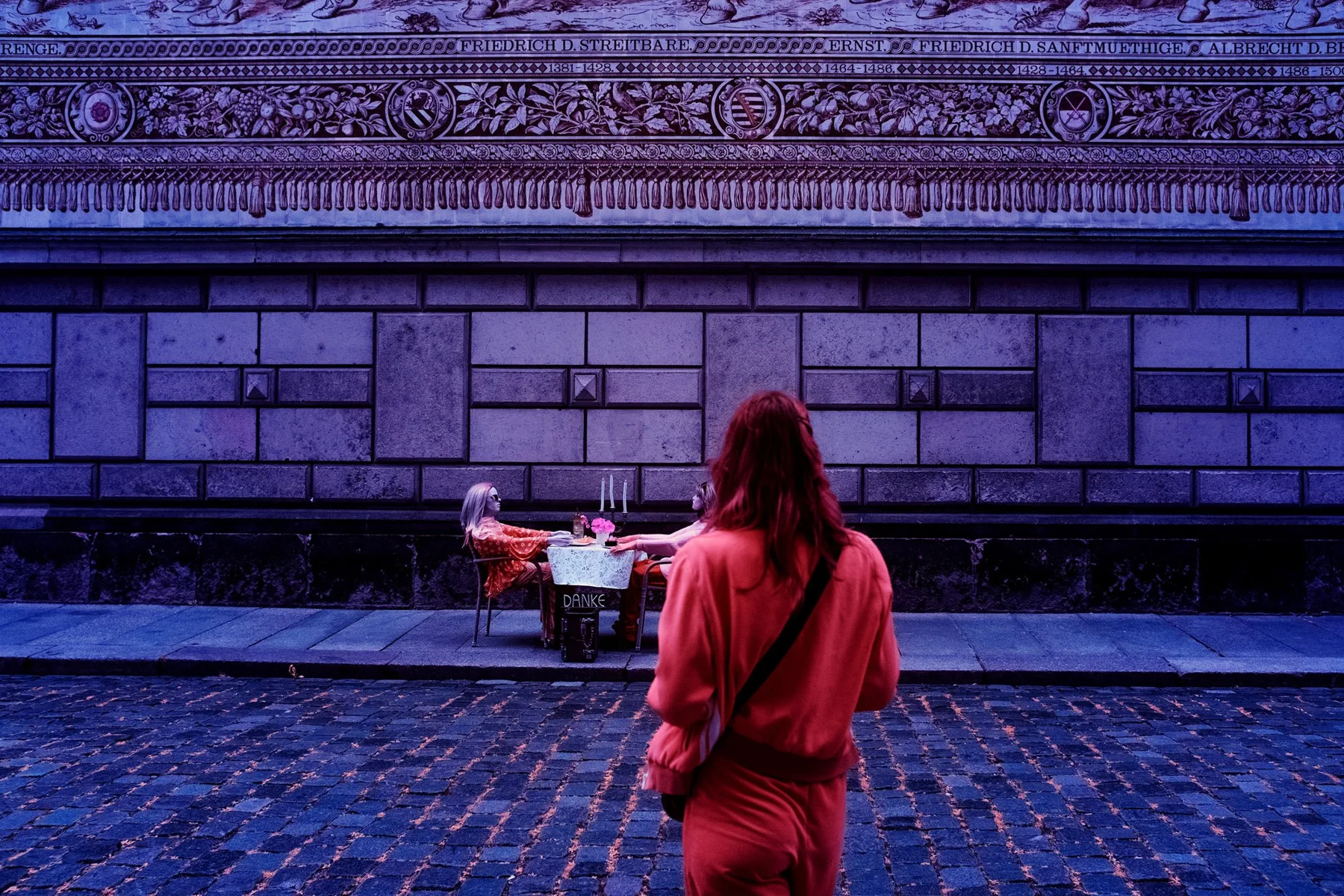 Une personne regarde des musiciens de rue devant une fa&ccedil;ade historique.