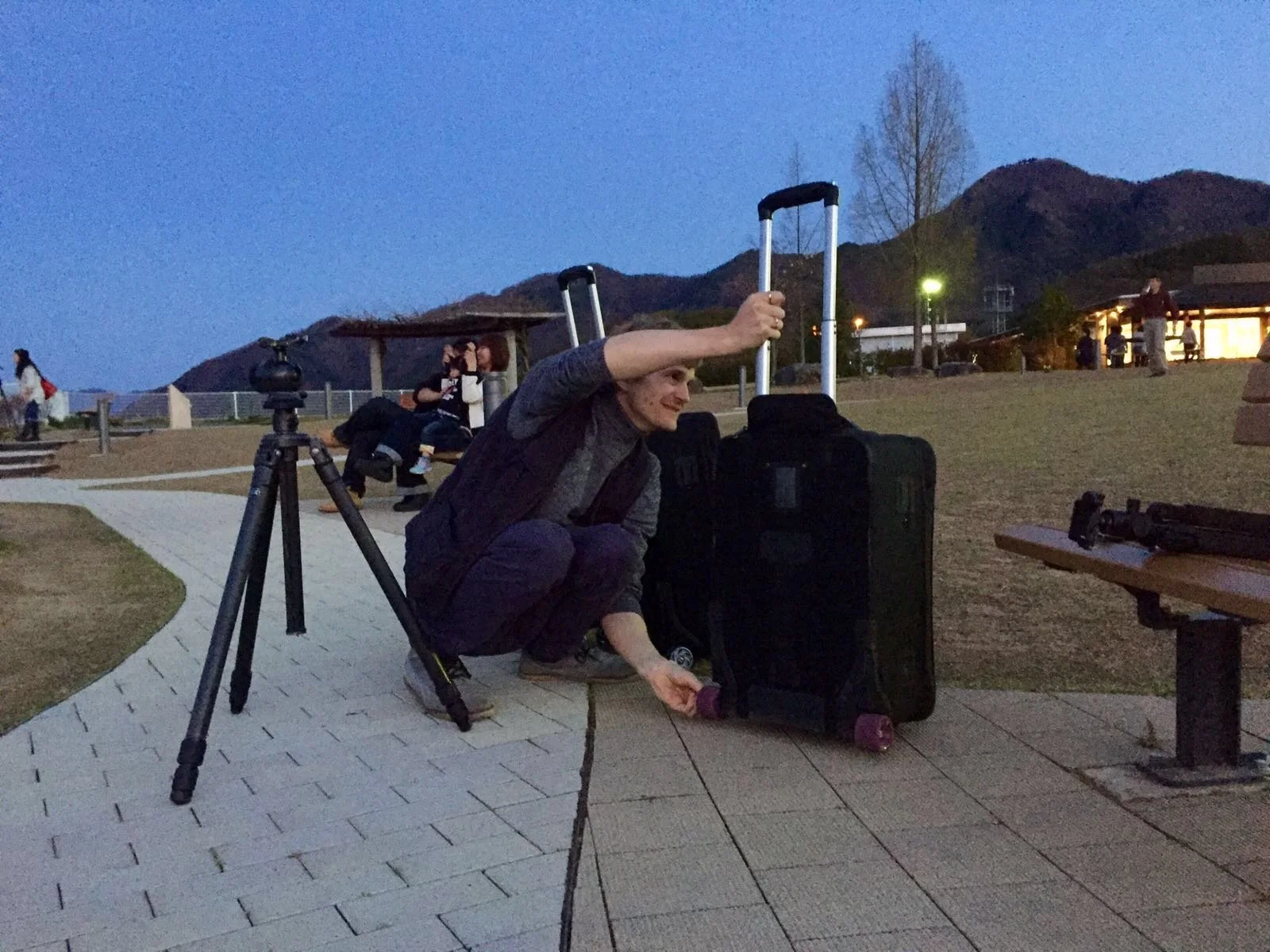 Photographe avec un tr&eacute;pied devant un paysage montagneux au cr&eacute;puscule