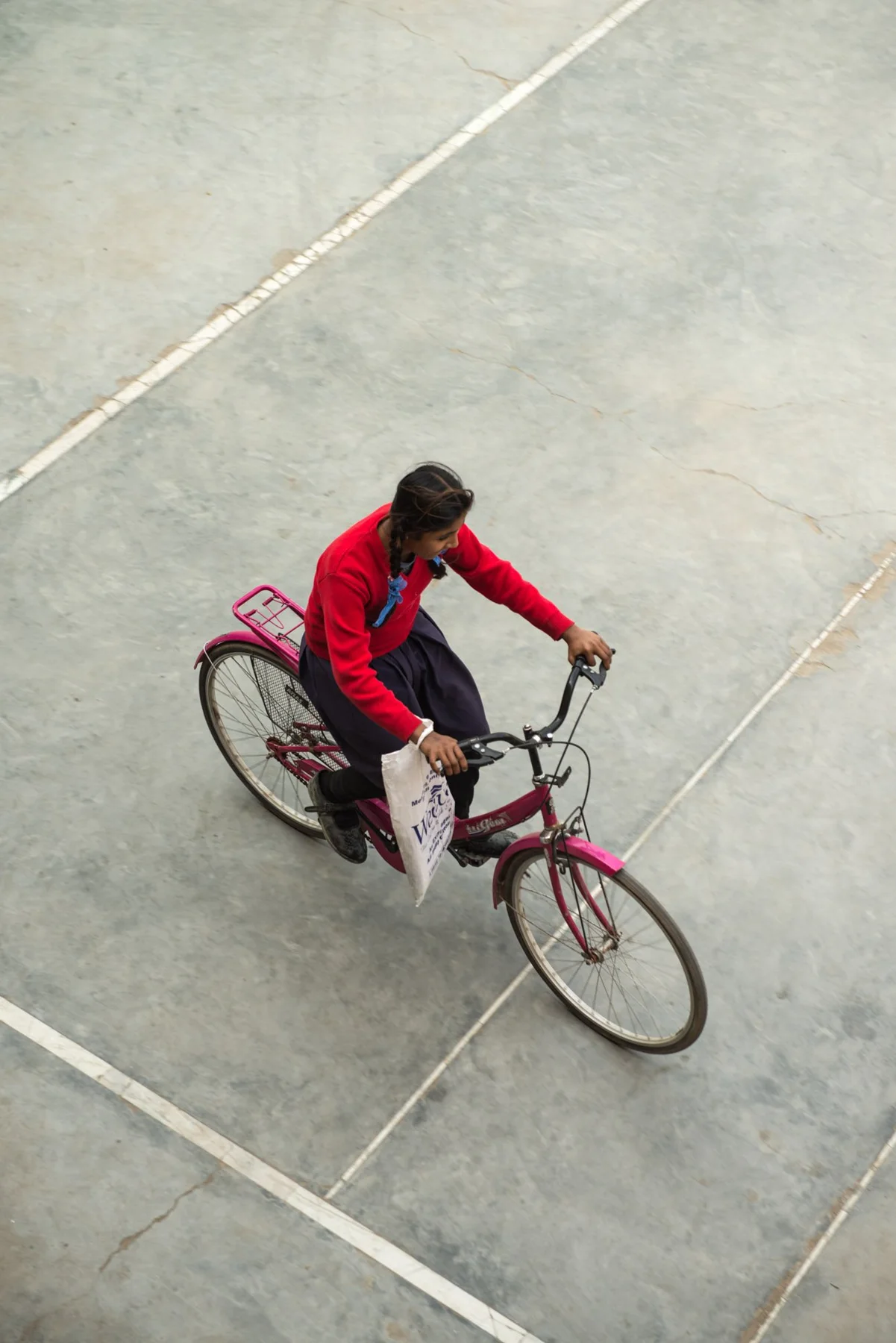 Fotografie einer Person in Rot auf einem Fahrrad, von oben gesehen