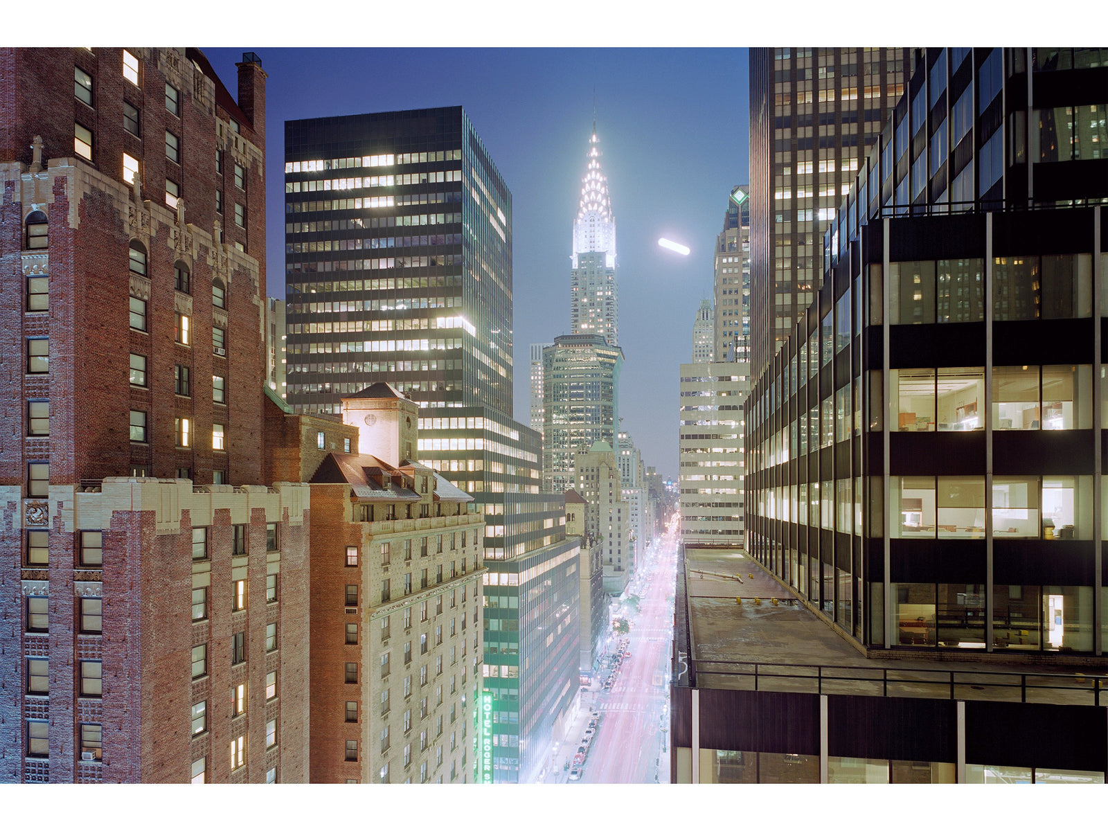 Fine art photography by André Wagner: A luminous street recedes into the night between tall rows of buildings — Fullmoon in manhattan, Usa.