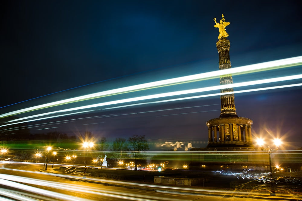 Photographie d’art d’André Wagner: Une haute colonne surmontée d’une figure dorée se dresse devant un ciel nocturne sombre — Golden Nights - Nothing Else.