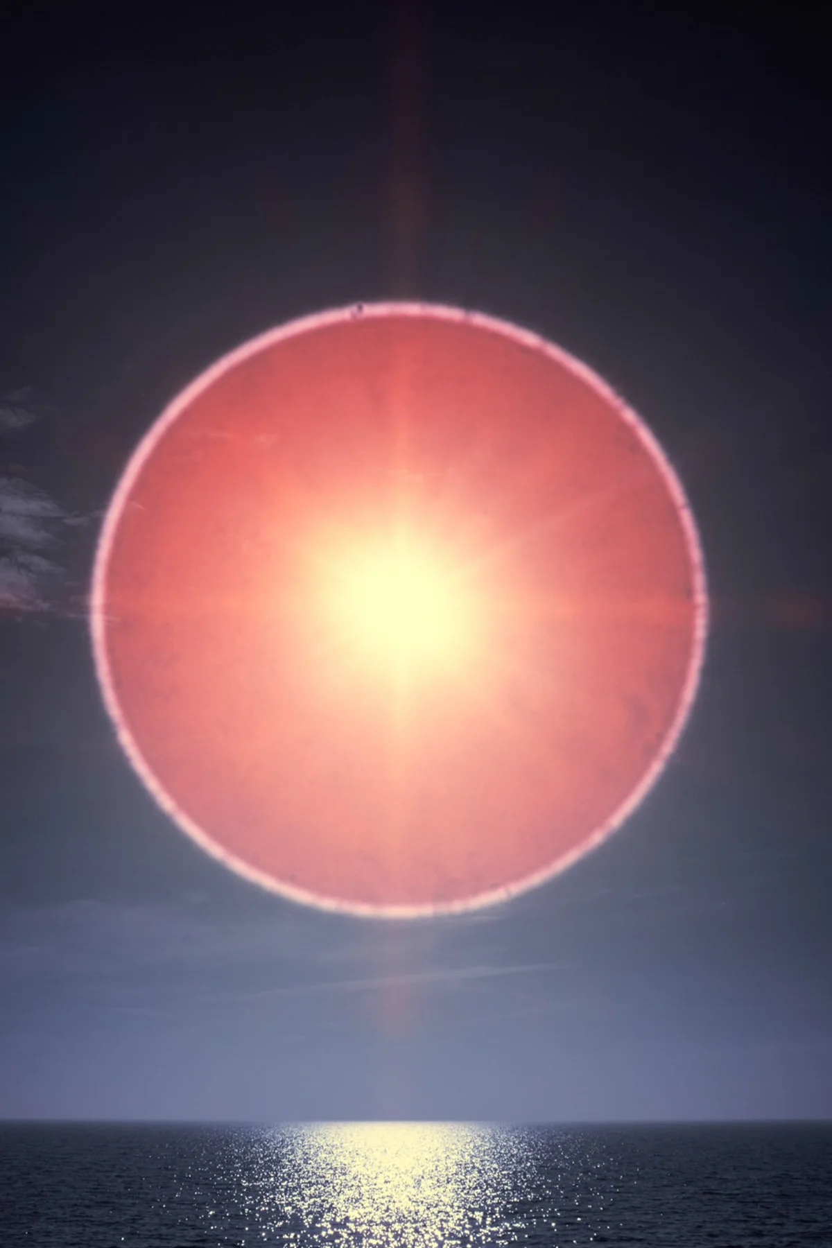 Grand cercle de lumi&egrave;re rouge au-dessus de la mer.