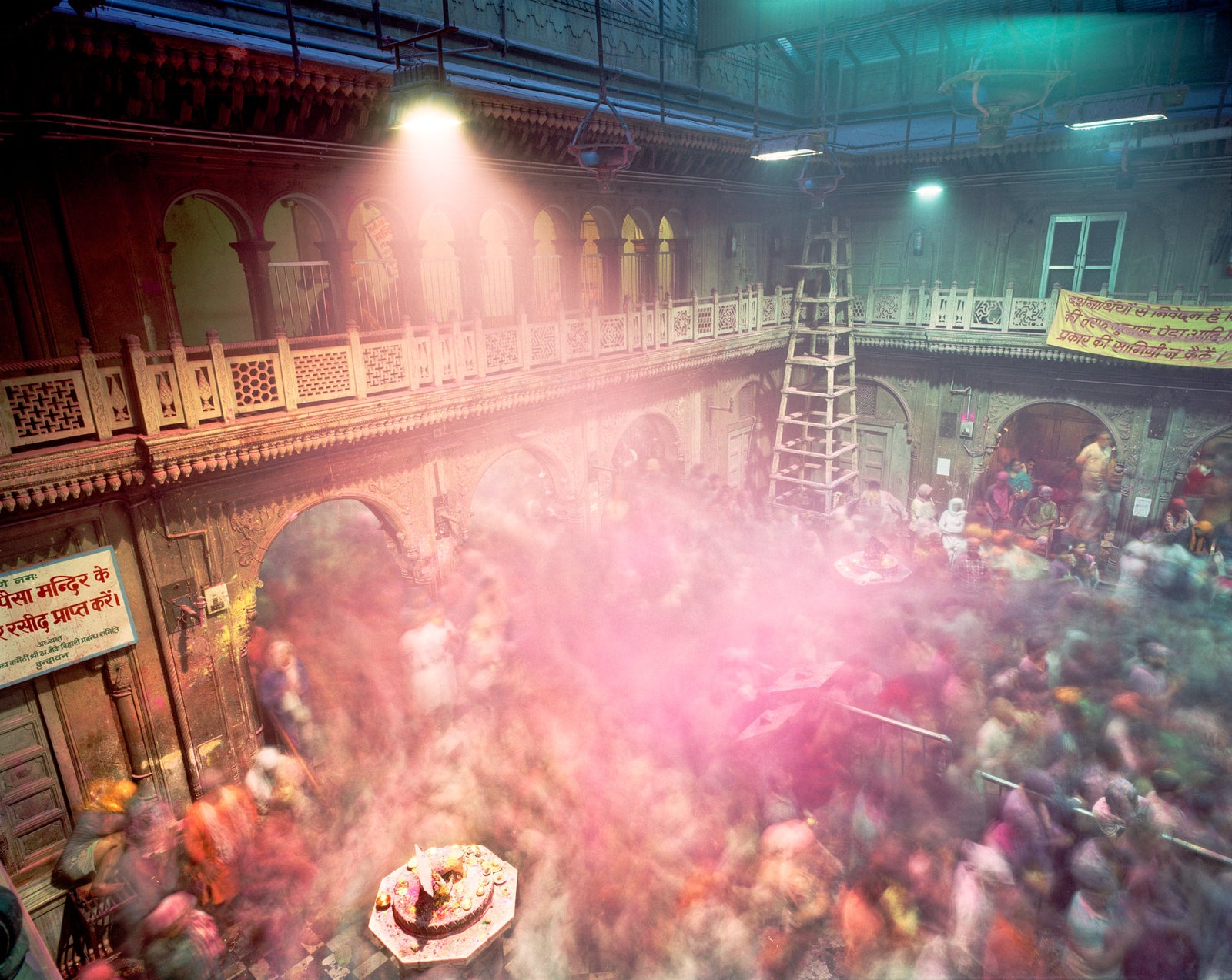 Photographie d&rsquo;art d&rsquo;Andr&eacute; Wagner: Une haute cour int&eacute;rieure s&rsquo;ouvre sous une zone de toiture sombre &mdash; Holi Bankey Bihari Temple 1, Indien.