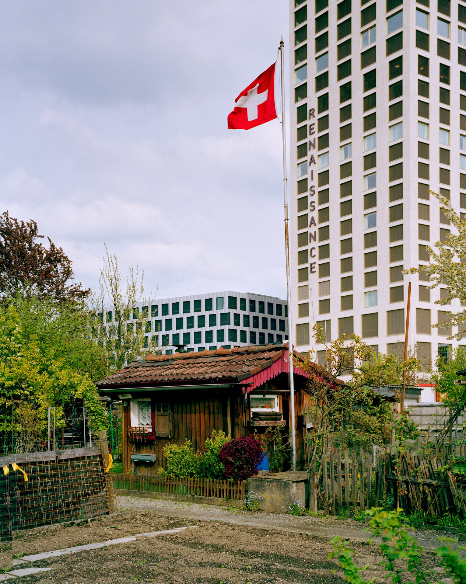 Photographie d’art d’André Wagner: Une petite cabane de jardin se tient derrière une clôture, des plantes et un chemin étroit — Kleingarten.