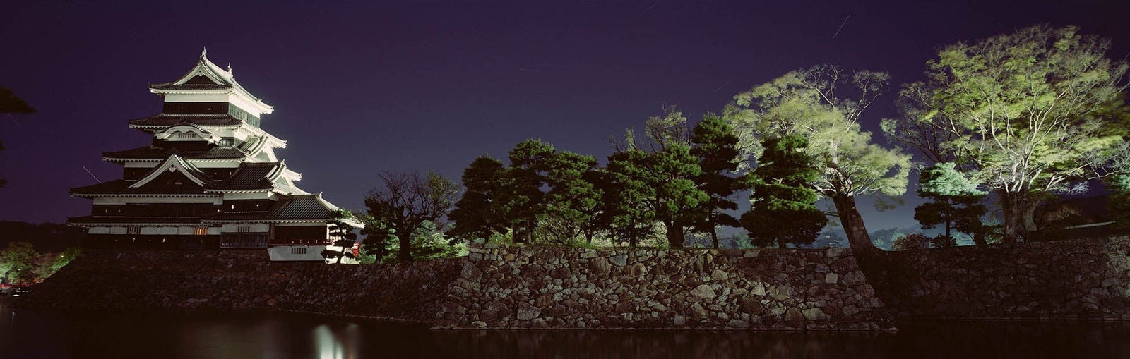 Fine art photography by André Wagner: A multistorey castle with prominent white roof edges stands on the left — Matsumoto castle, Japan.