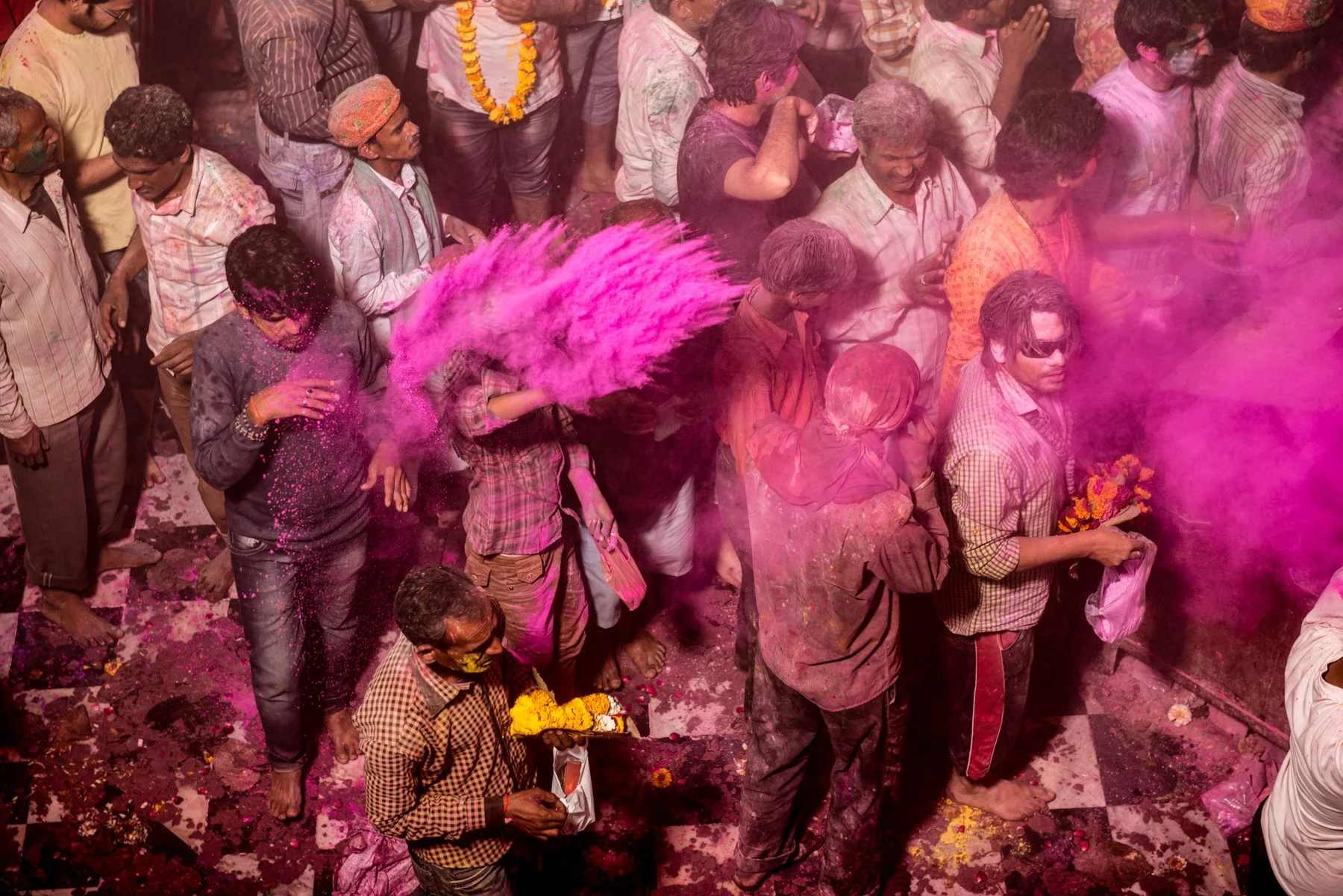 Menschen beim Holi-Fest unter einer Wolke pinkfarbenen Pulvers.