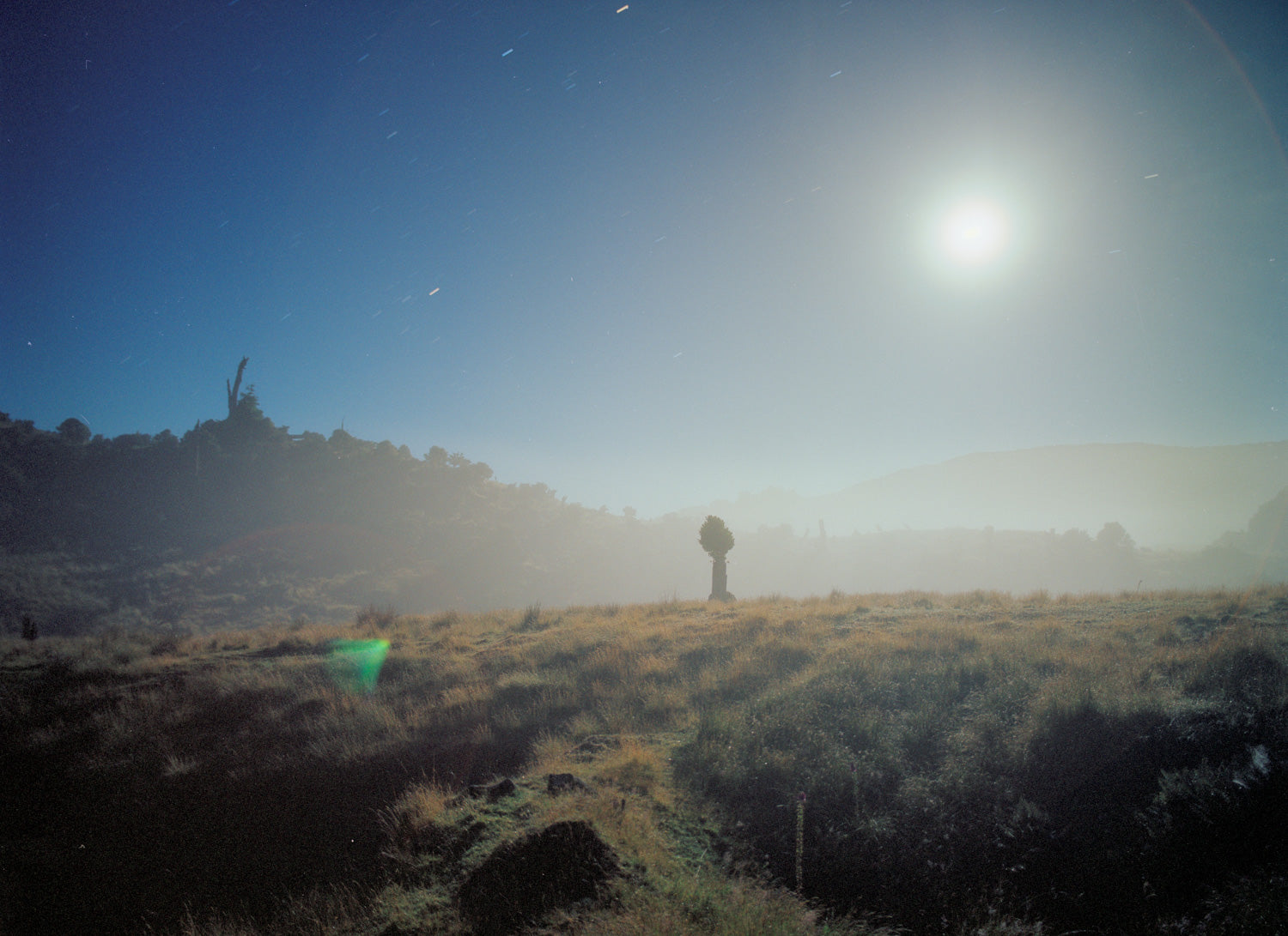 Photographie d’art d’André Wagner: Une petite figure humaine se tient dans un paysage vaste et bas — Moonset.