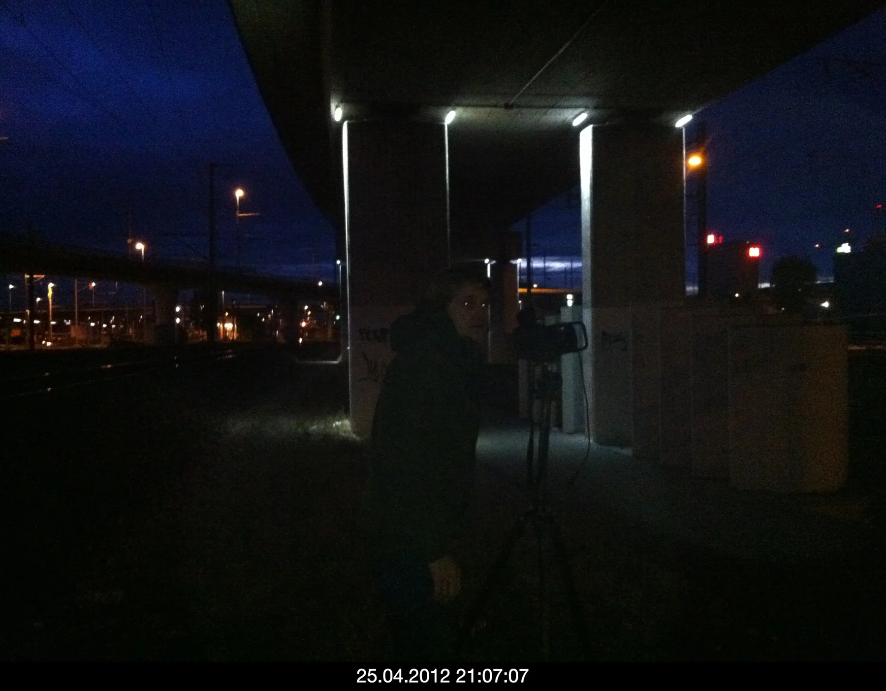 Night photograph of a person with a tripod beside an illuminated building