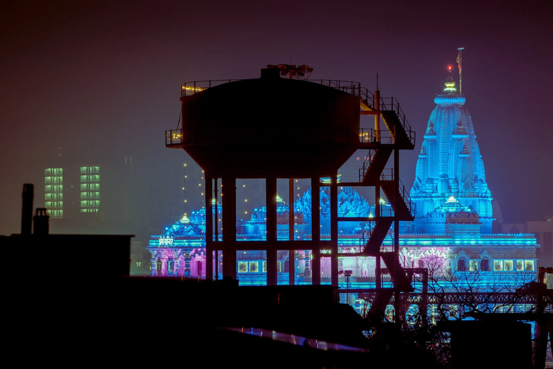 N&auml;chtliche Fotokunst mit Wasserturm als Silhouette vor beleuchteten Hochh&auml;usern