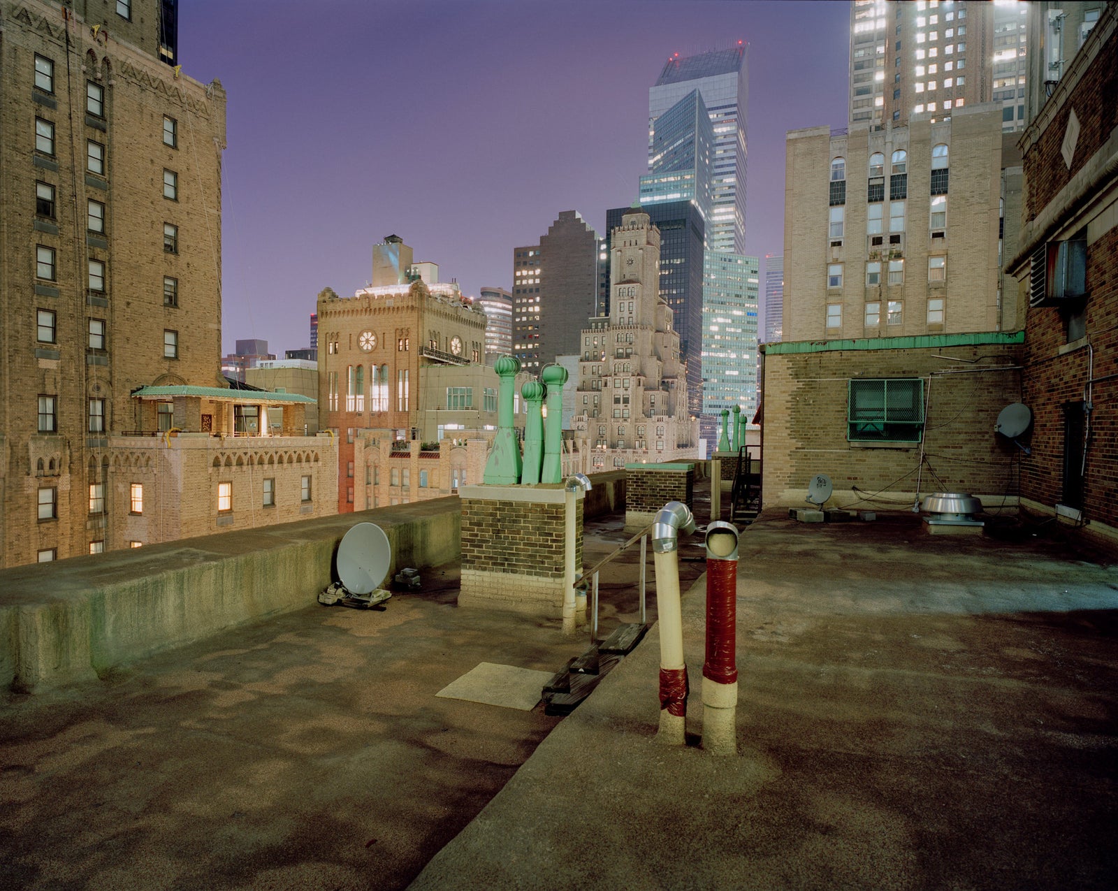Photographie d’art d’André Wagner: Un toit plat bordé d’un parapet bas se trouve entre des immeubles serrés les uns contre les autres — NY Roof.