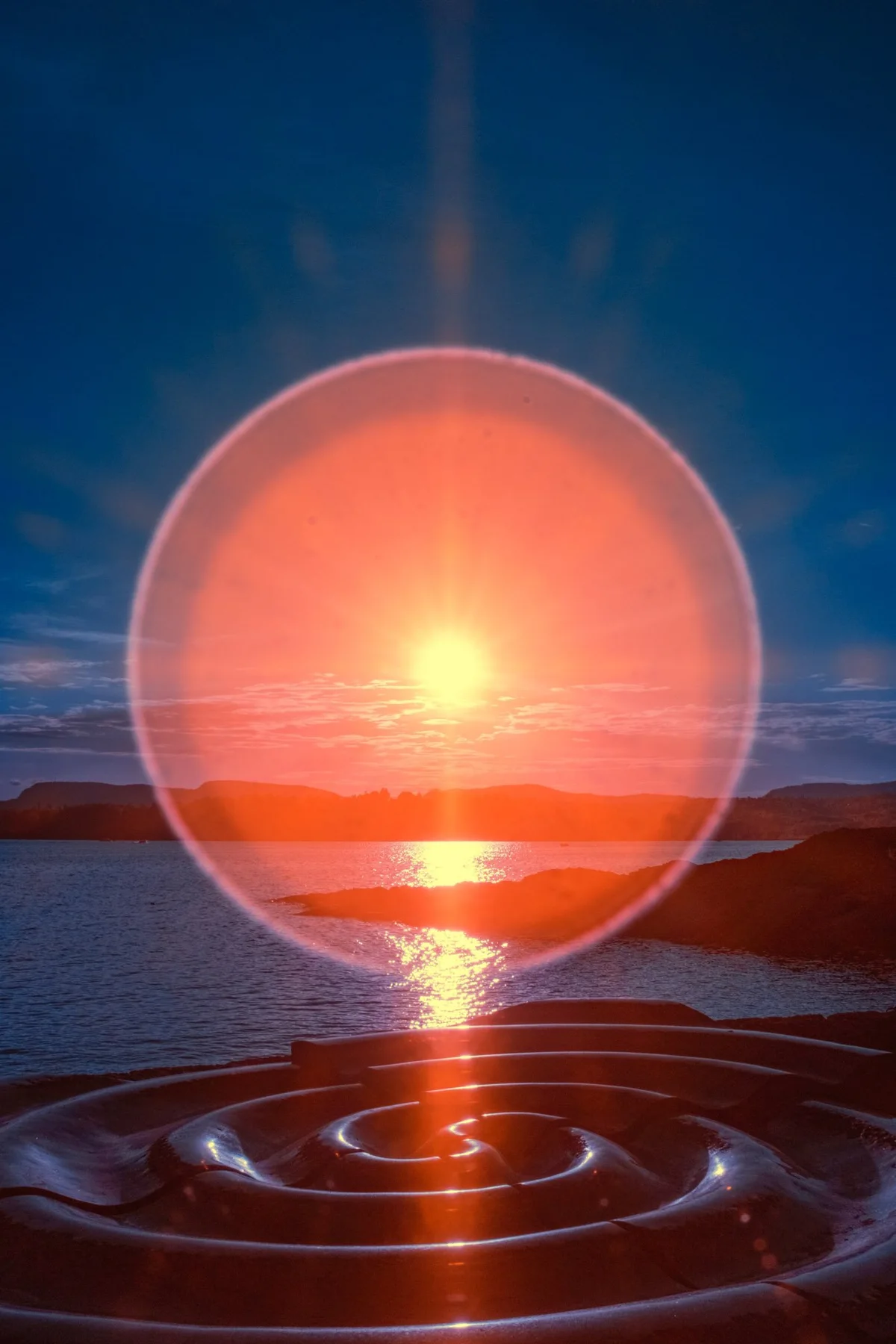 Cercle de lumi&egrave;re orange au-dessus des reflets du soleil sur la mer.