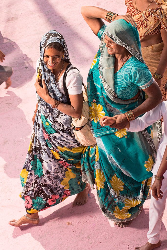 Fine art photography by André Wagner: Two women walking close together occupy the centre in differently patterned green, blue and dark clothing — Pilgrim on Purple Dust 11, Indien.