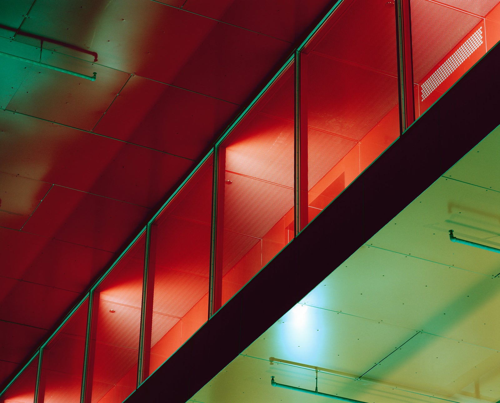 Photographie d’art d’André Wagner: Une large diagonale sombre sépare des surfaces rouge lumineux, en haut, d’une zone claire verdâtre, en bas — Red Floor.