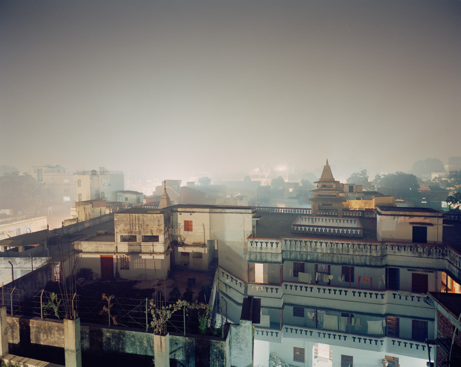 Photographie d’art d’André Wagner: Une brume gris clair enveloppe des toits et des façades densément étagés — Room of Mantra.