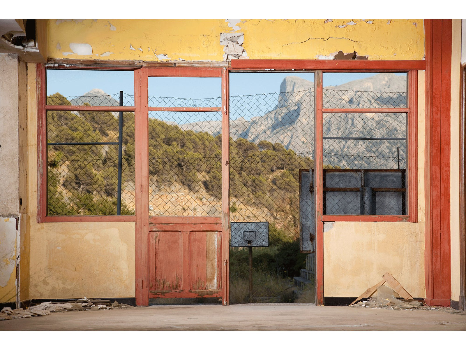 Photographie d’art d’André Wagner: Un mur jaune endommagé encadre une porte rouge et de grandes ouvertures de fenêtres — Salon - old hotel, Spanien.