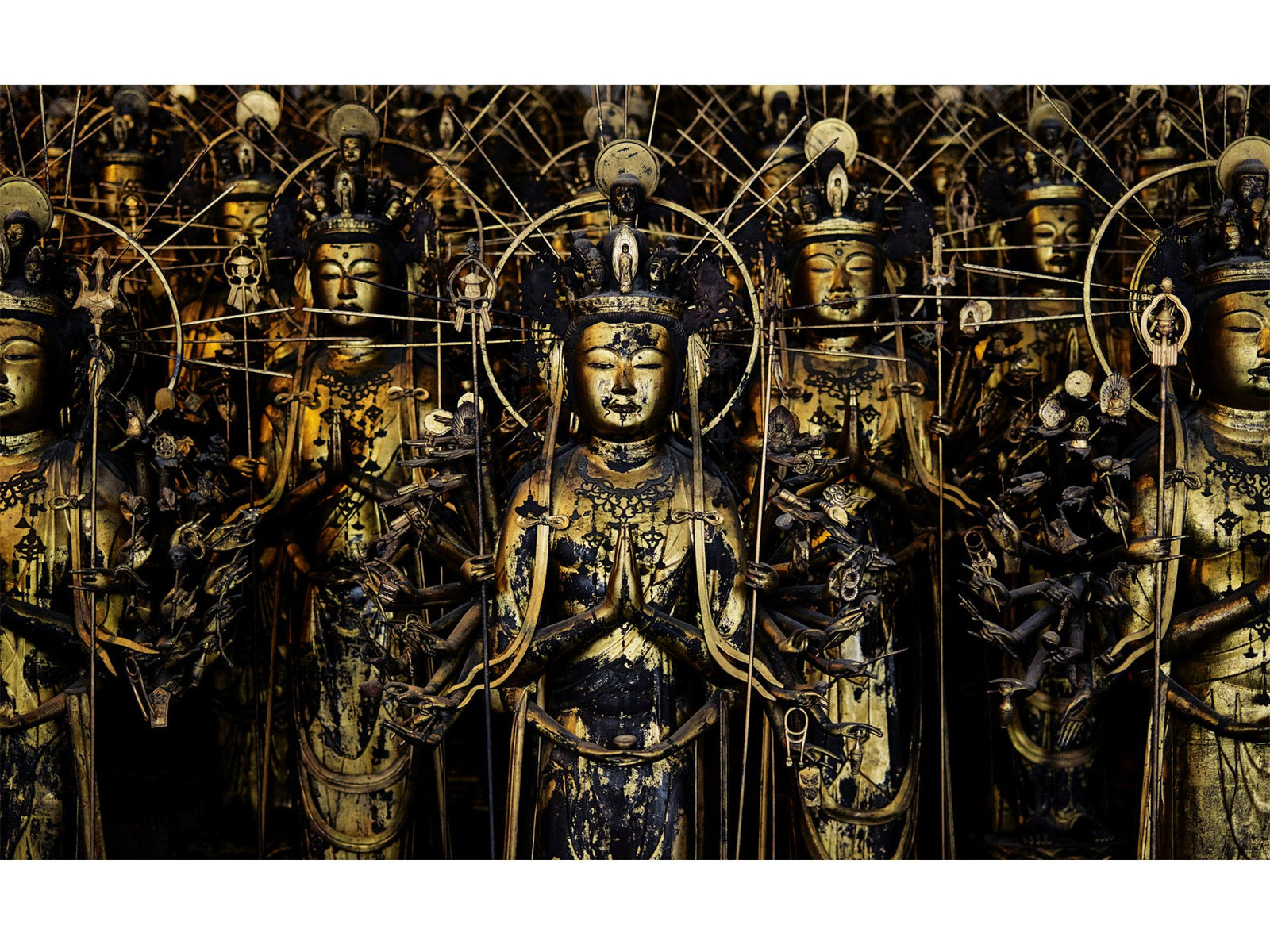 Fine art photography by André Wagner: Golden figures stand close behind one another, filling the image to its edges — Sanju sangen-do, Japan.