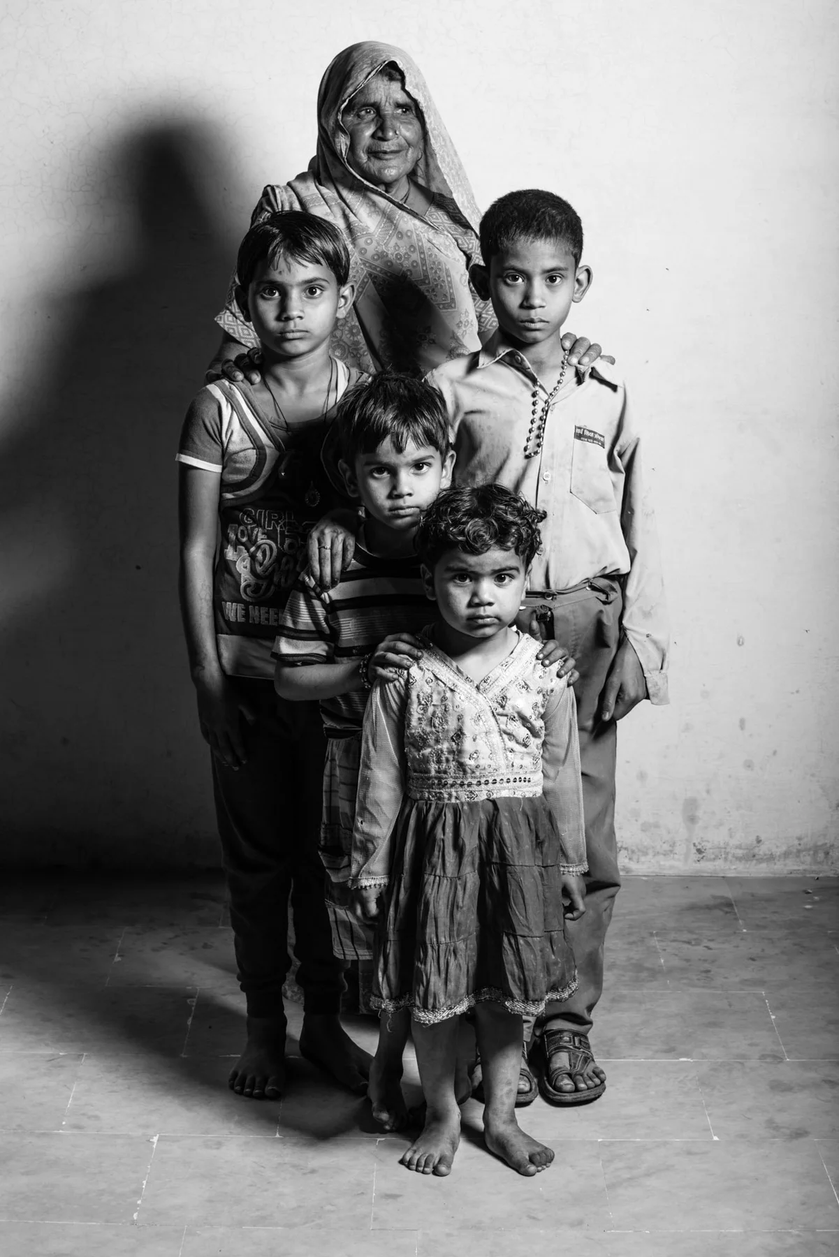 Schwarz-Wei&szlig;-Gruppenportr&auml;t einer Frau mit mehreren Kindern vor einer Wand.