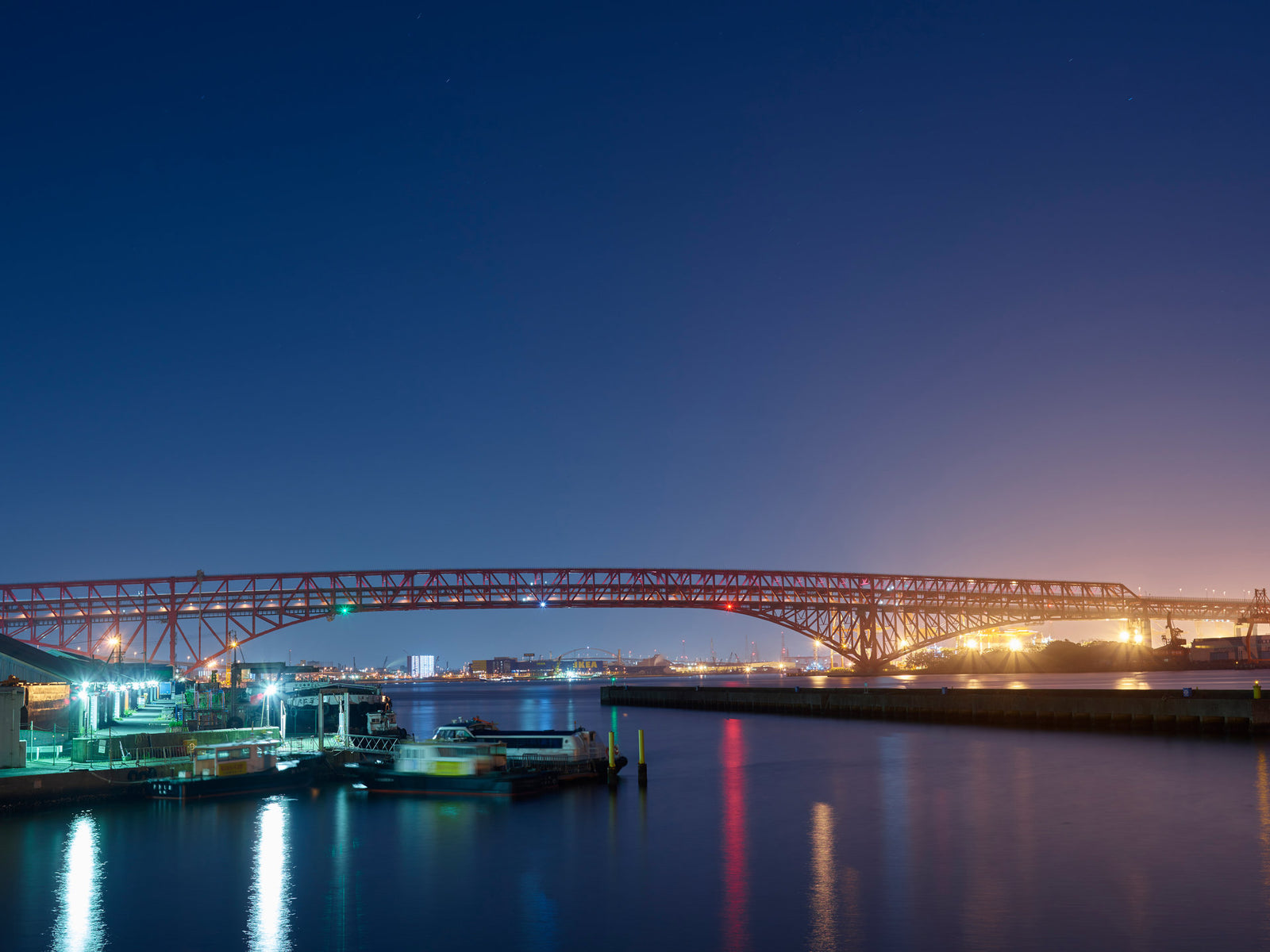 Photographie d’art d’André Wagner: Un long pont dessine une courbe basse dans la moitié inférieure de l’image — Skyline Osaka 2.