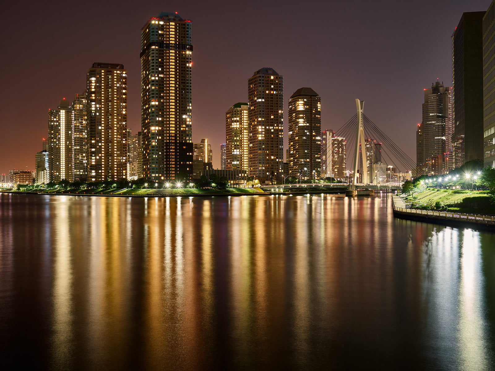 Fine art photography by André Wagner: Tall, densely windowed buildings stand across the water — Skyline tokyo, Japan.