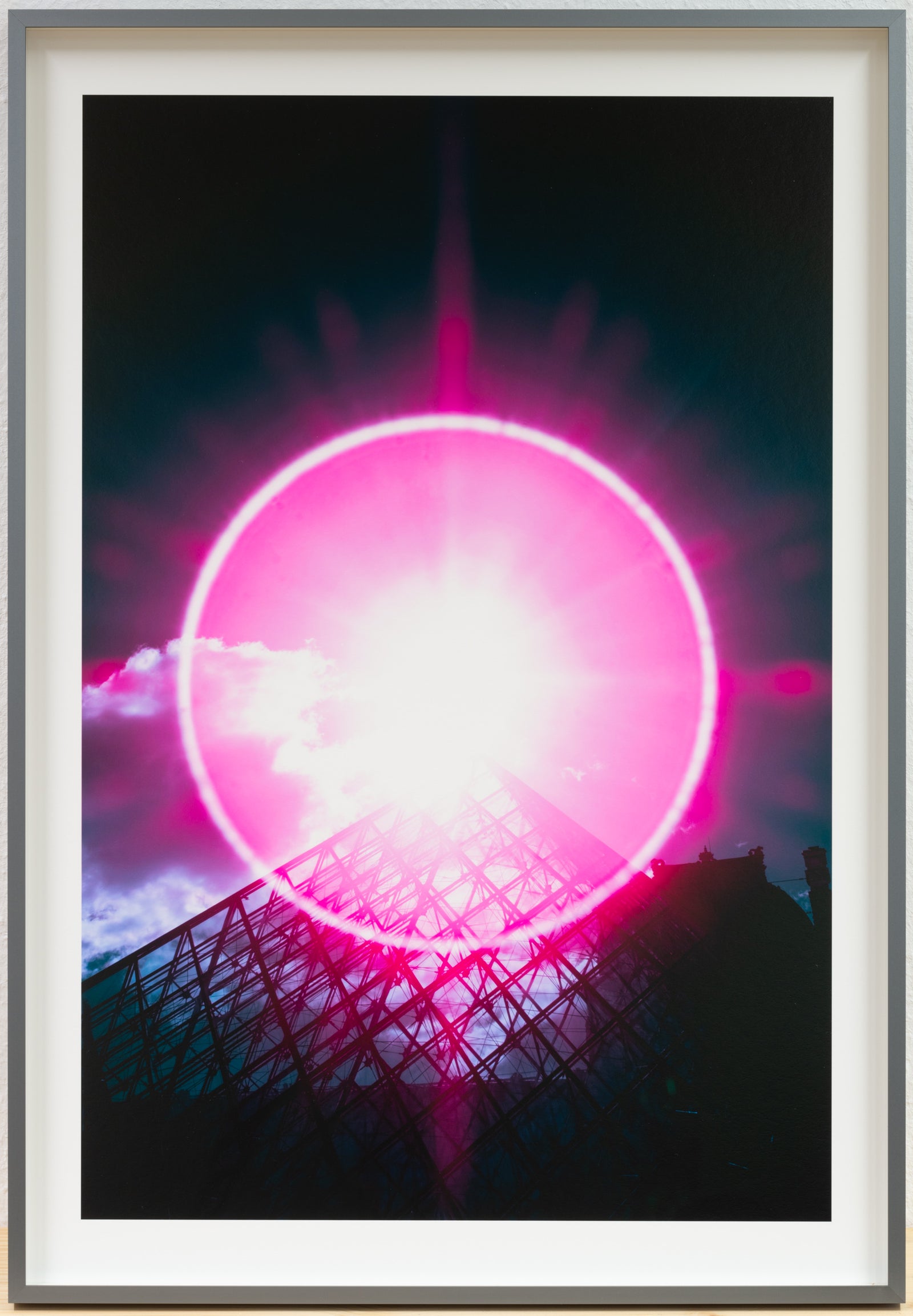 Photographie d’art infrarouge d’André Wagner: Un cercle lumineux d’un rose intense se déploie au-dessus d’une structure de verre montant en diagonale — Spectrum of enlightenment: halo above the louvre, Frankreich.