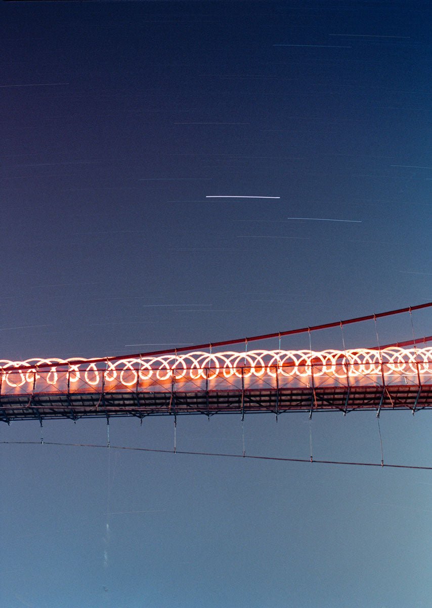 Photographie d’art d’André Wagner: Une rangée de boucles dorées traverse horizontalement une zone paysagère sombre et calme — Star Walk, Indien.