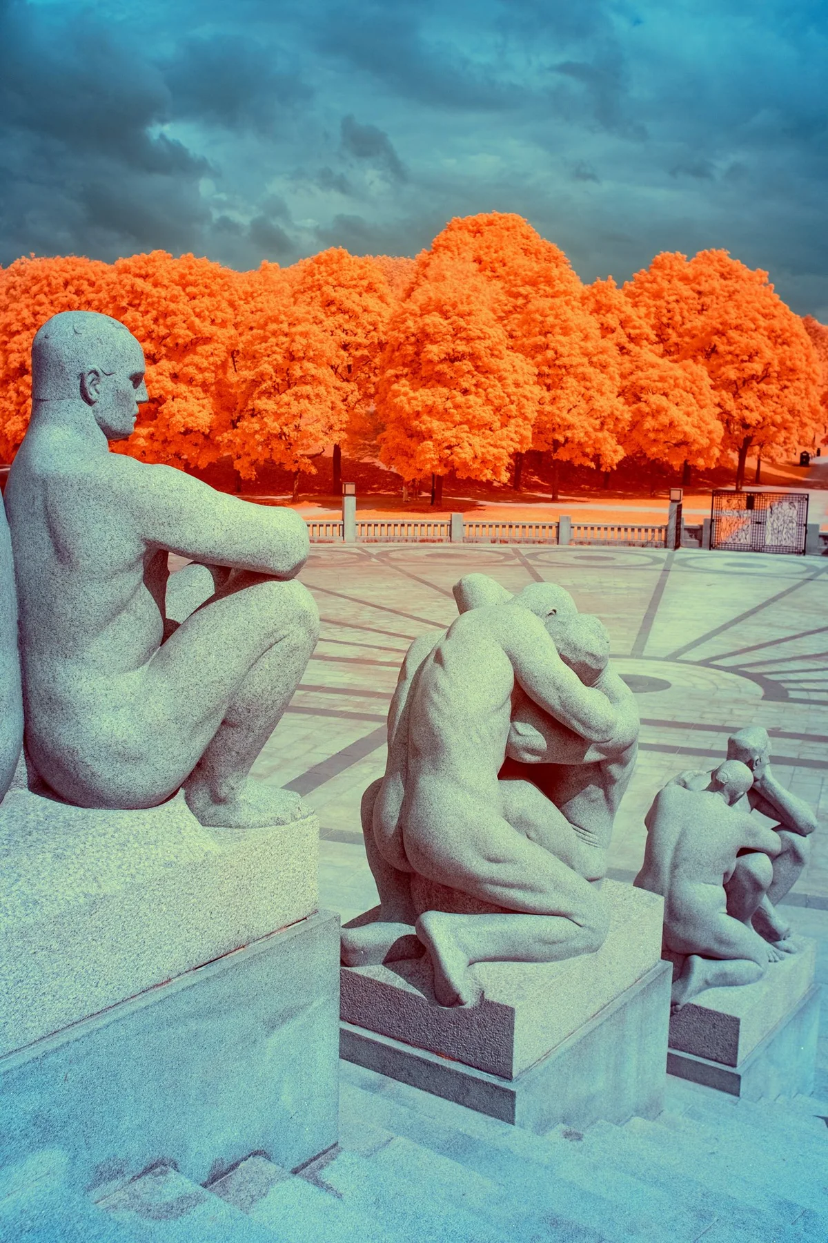 Figures de pierre devant une rang&eacute;e d&rsquo;arbres orange.