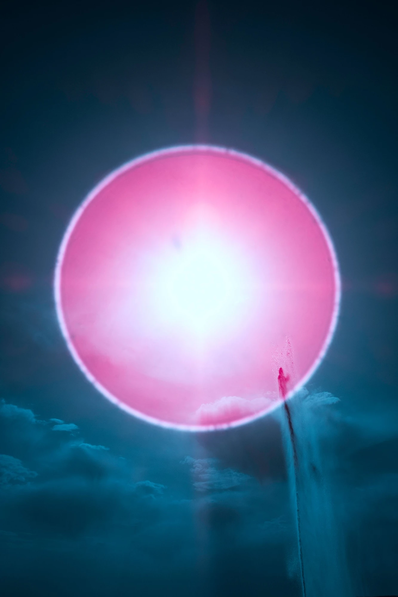 Photographie d’art infrarouge d’André Wagner: Un cercle rose lumineux occupe presque toute la largeur du cadrage vertical sombre — SUN HALO AND FOUNTAIN.