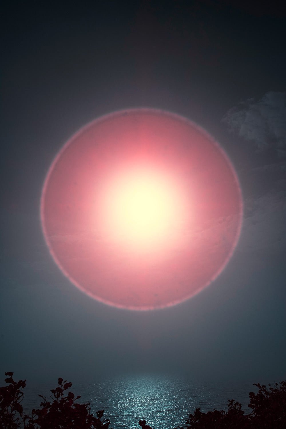 Photographie d’art infrarouge d’André Wagner: Un grand cercle de lumière rose occupe le centre d’un ciel sombre — Sun halo: play of light over ocean waves 2, Deutschland.