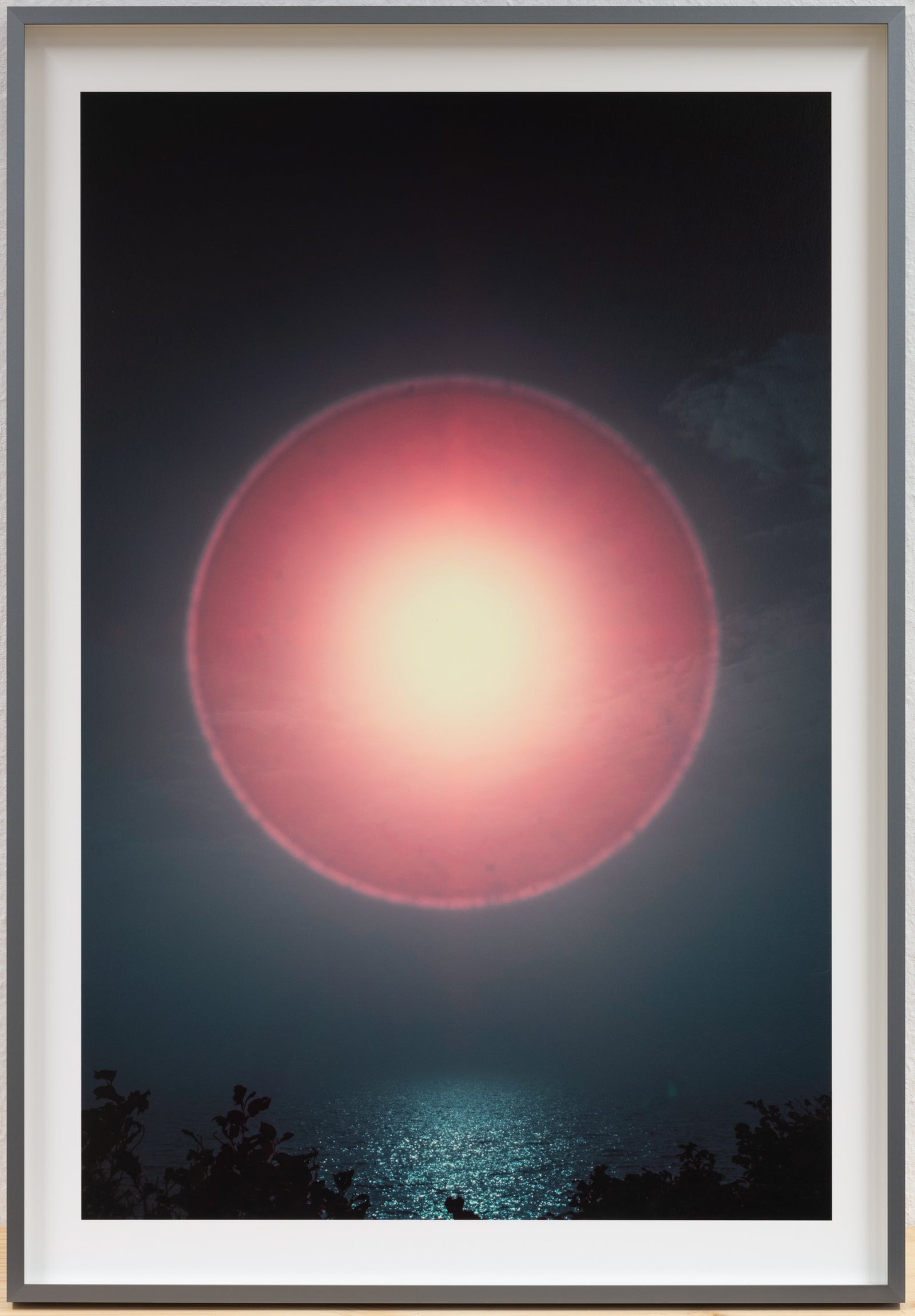 Photographie d’art infrarouge d’André Wagner: Un cercle de lumière rose occupe les parties supérieure et centrale de cette vue sombre — Sun halo: play of light over ocean waves 2, Deutschland.