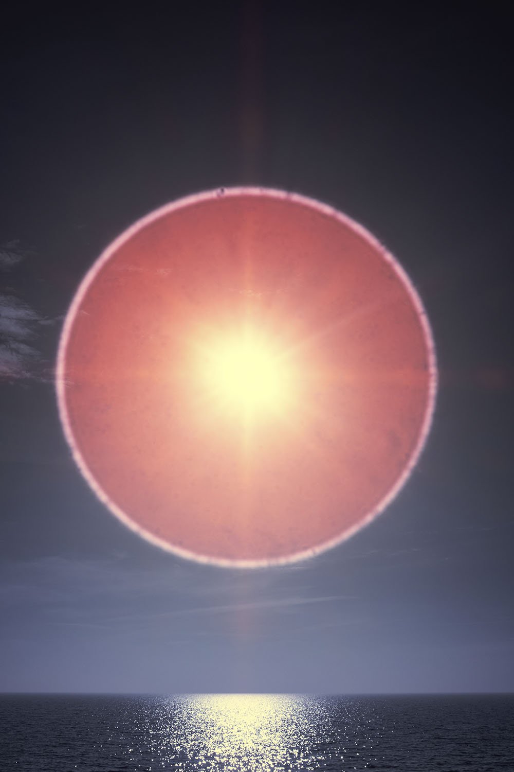 Photographie d’art infrarouge d’André Wagner: Au-dessus de l’horizon rectiligne de la mer se tient un grand cercle de lumière rose rougeâtre, au bord nettement lumineux — Sun halo: play of light over ocean waves 3, Deutschland.