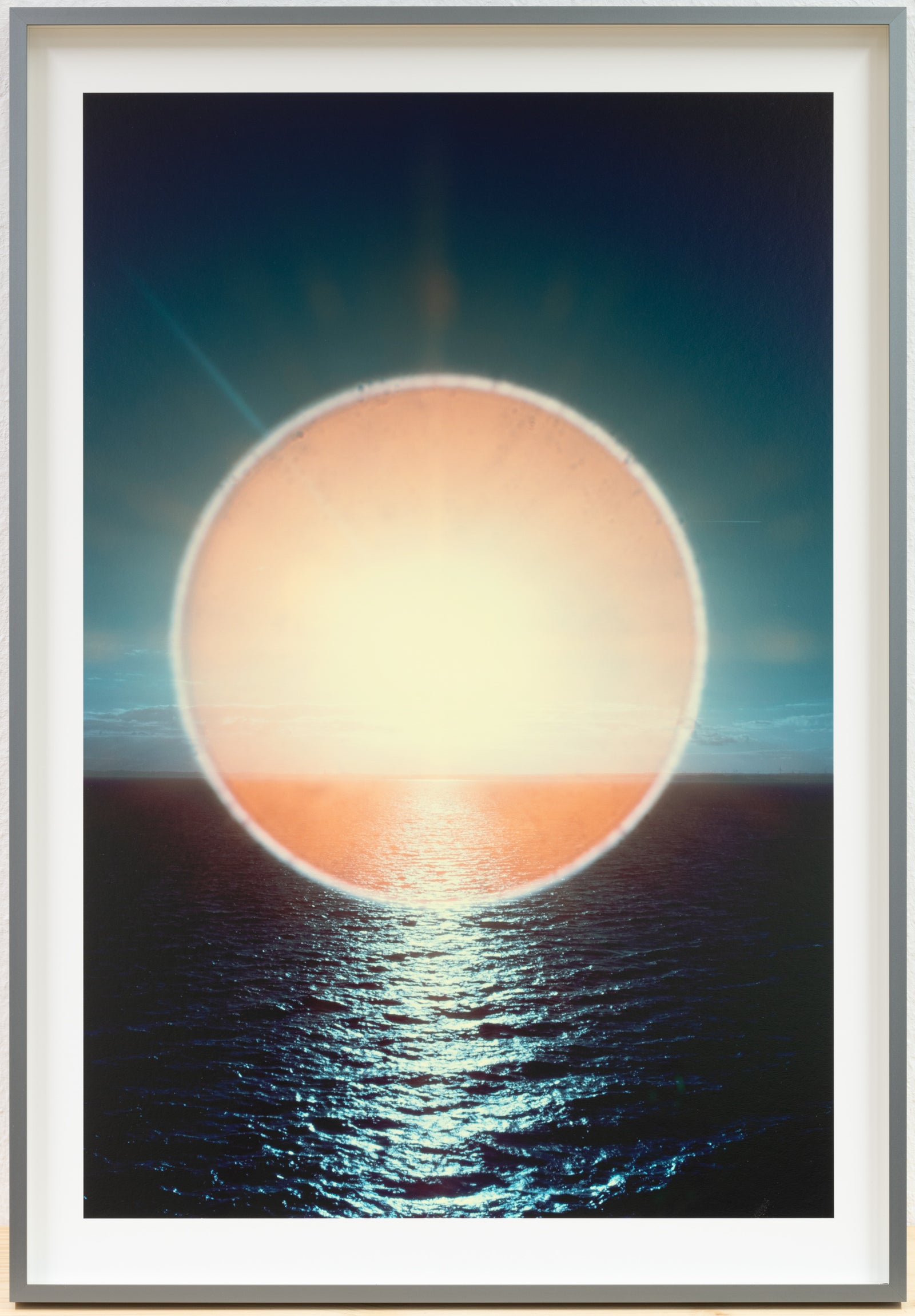 Photographie d’art infrarouge d’André Wagner: Un grand cercle de lumière or pâle se tient exactement au-dessus de la mer sombre et coupe l’horizon — Sun halo: play of light over ocean waves, Deutschland.