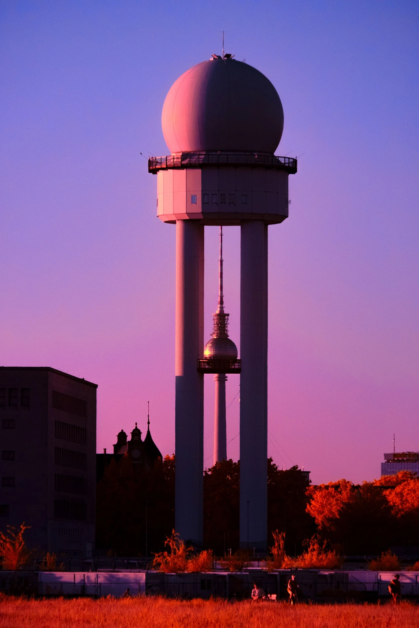 Photographie d’art infrarouge d’André Wagner: Une tour à sommet sphérique se dresse, imposante, devant un ciel rose-violet — Tempelhof Perspective.