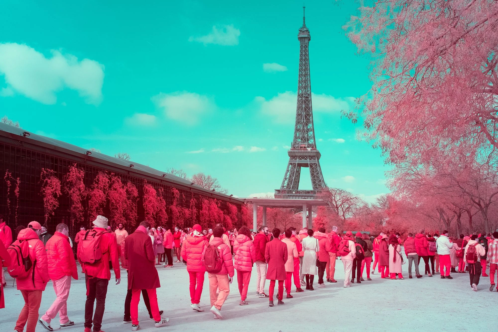 Photographie d’art infrarouge d’André Wagner: La tour Eiffel occupe le centre de l’image, mais les personnes qui attendent déterminent le premier plan — The Symbol and the Queue.