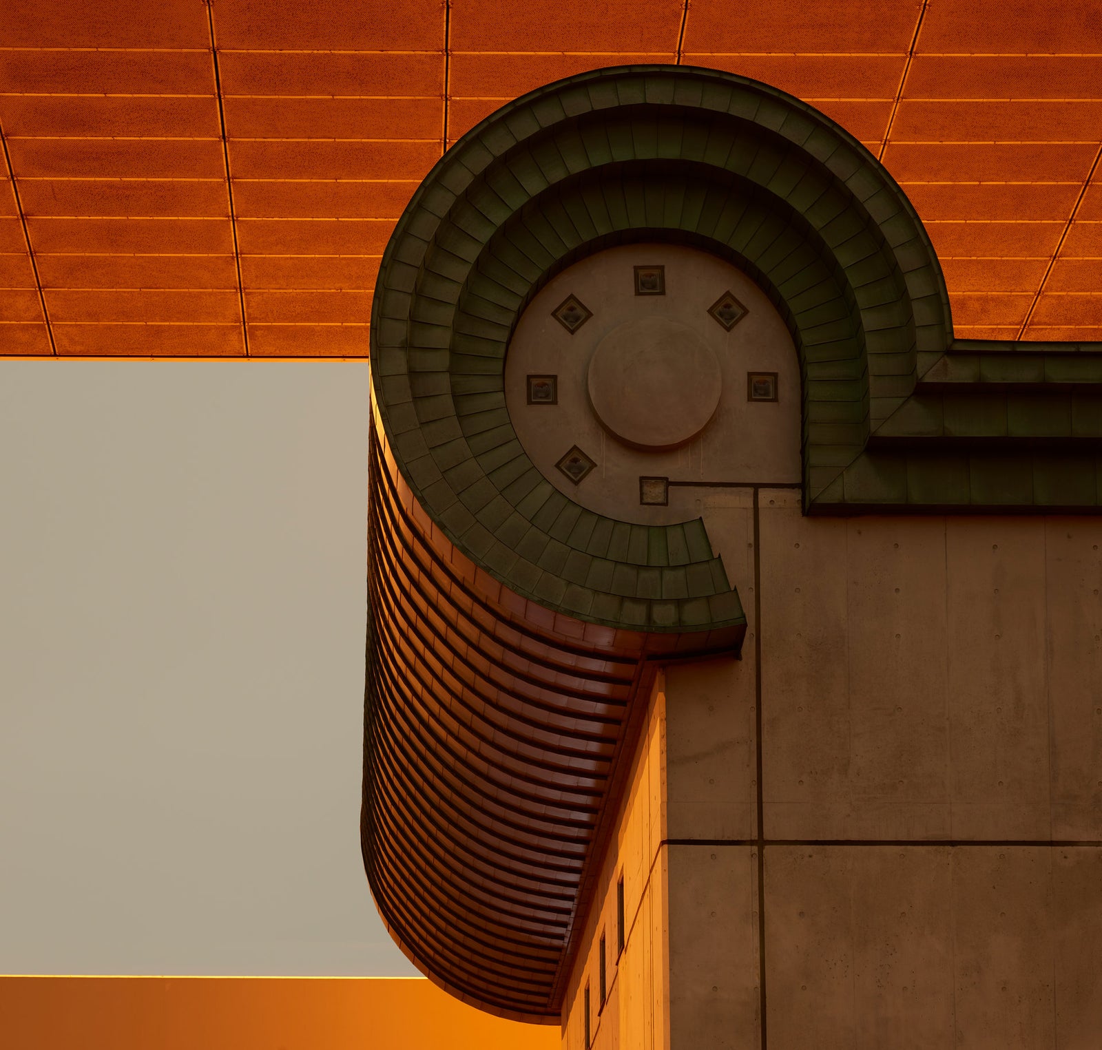 Photographie d’art d’André Wagner: Un élément architectural terminal, sombre et arrondi, se détache devant un plafond orange — Tokyo 1.