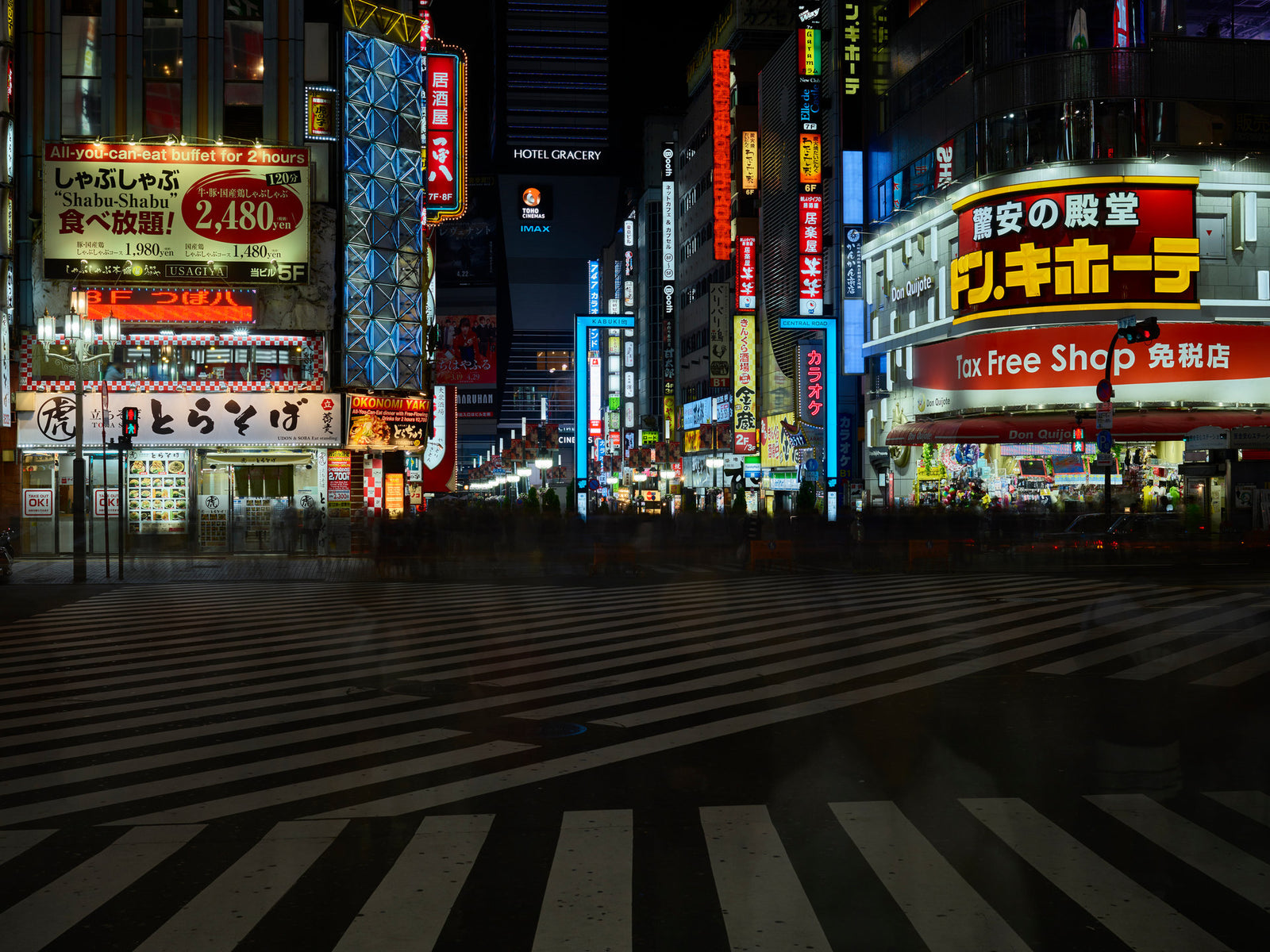Photographie d’art d’André Wagner: Les bandes blanches d’un passage piéton s’évasent sur le premier plan sombre — Tokyo Shinjuku 3.