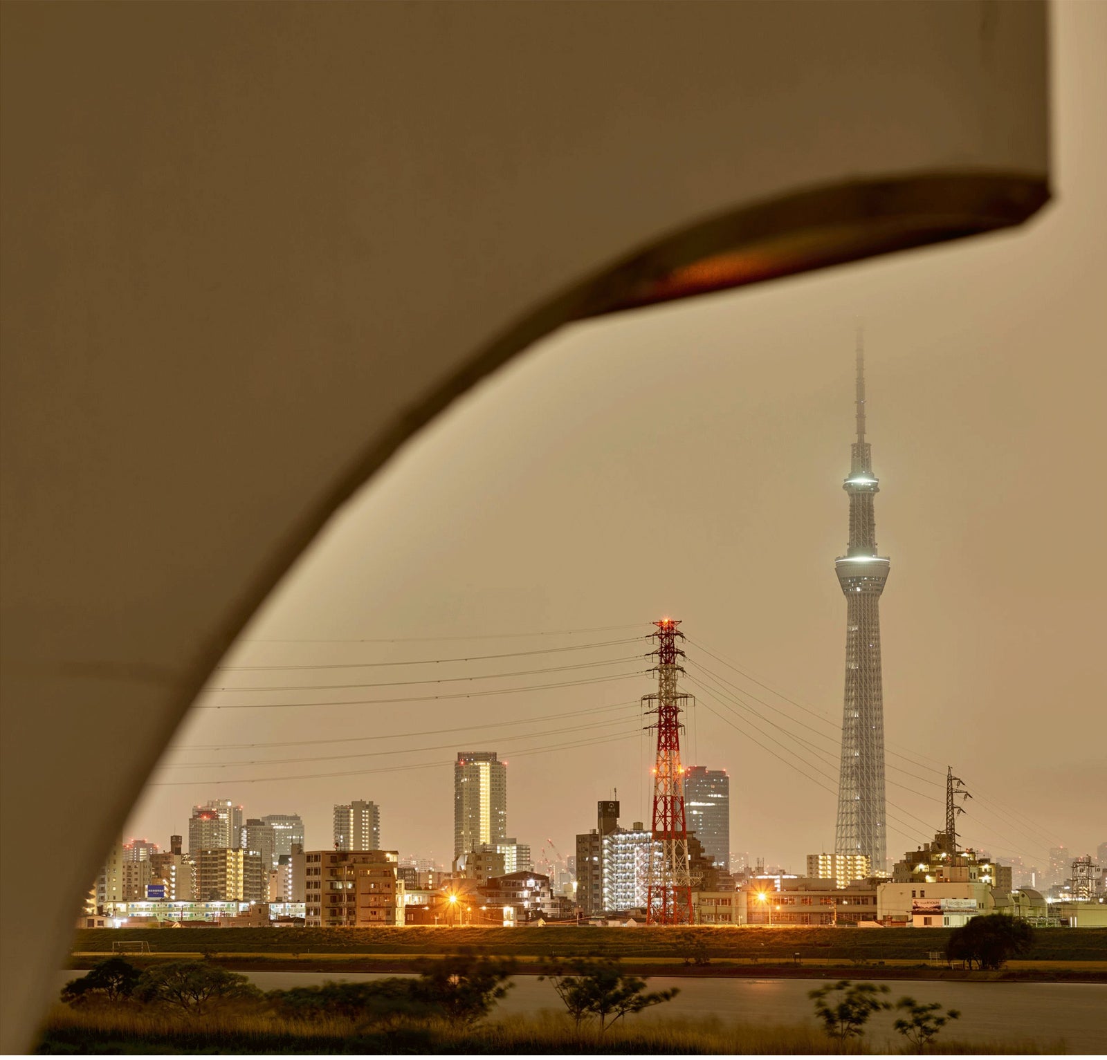 Fine art photography by André Wagner: A large dark curve crosses the foreground and frames the distant city — Tokyo skyline 1, Japan.