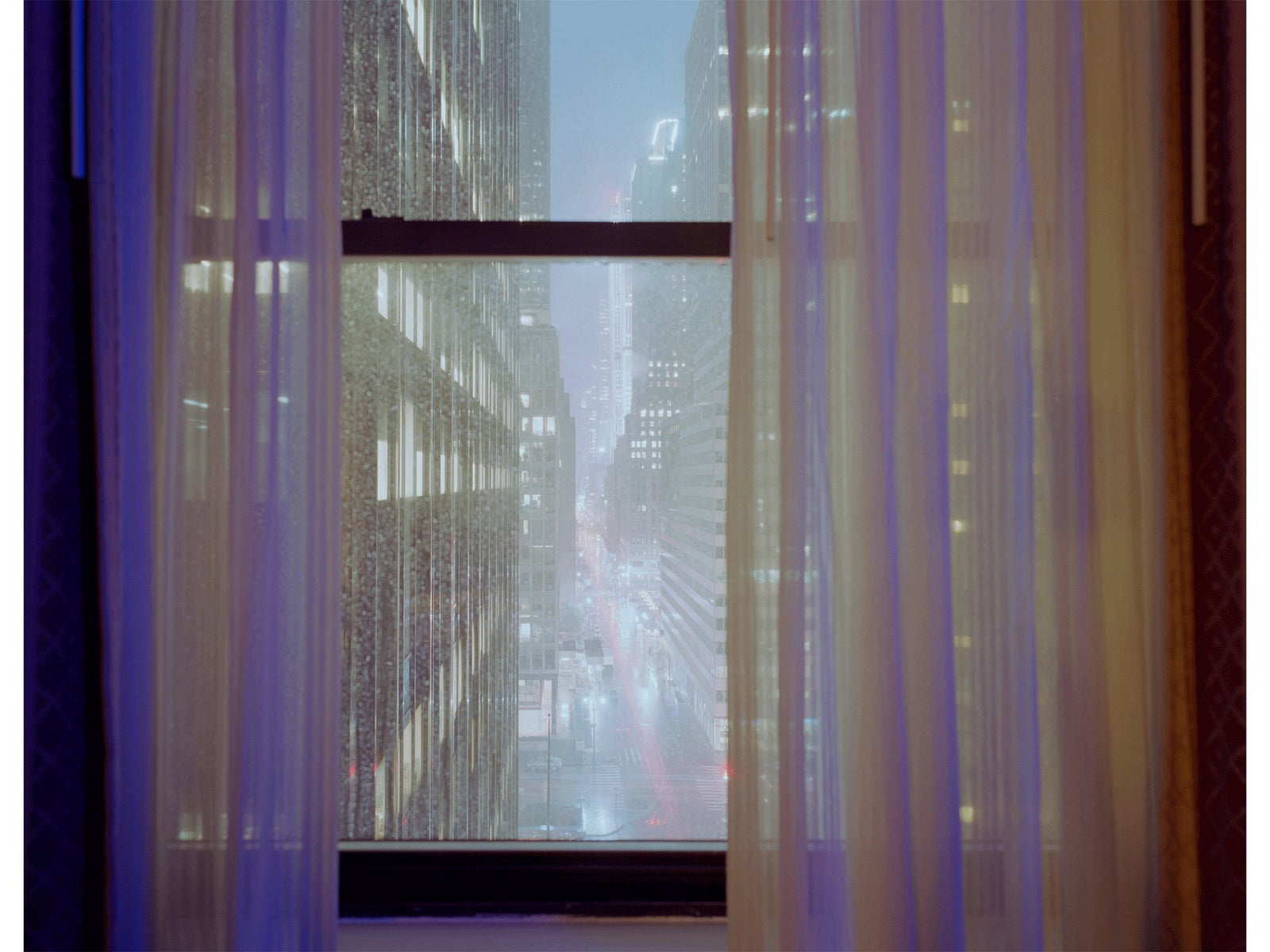 Photographie d’art d’André Wagner: Une haute fenêtre ouvre sur une étroite rue encaissée entre des bâtiments aux nombreuses fenêtres — View of manhattan, Usa.