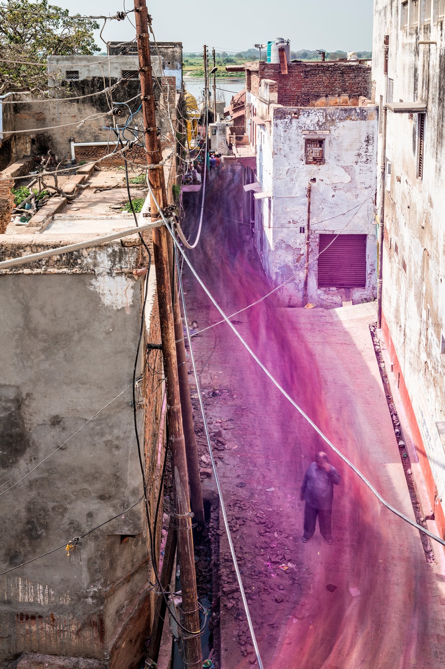 Fine art photography by André Wagner: A narrow lane recedes between pale house walls — Vrindavan flow, Indien.