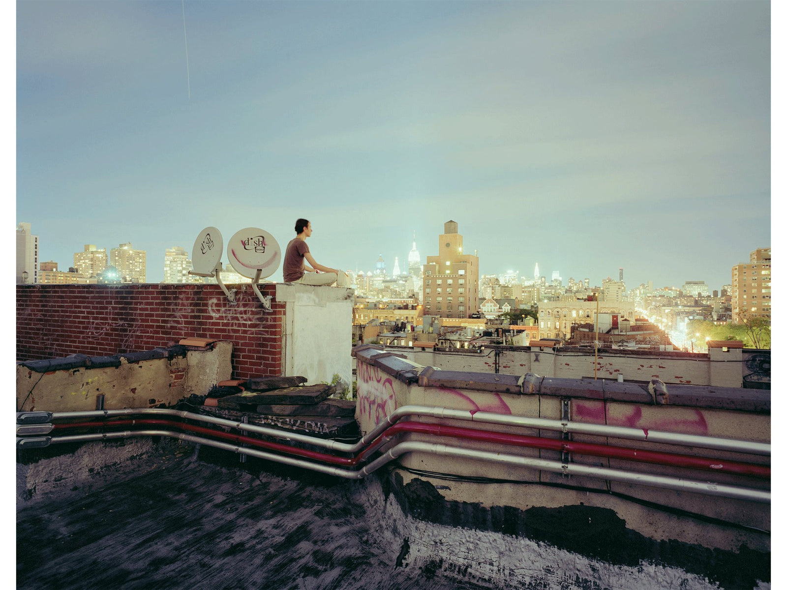 Photographie d&rsquo;art d&rsquo;Andr&eacute; Wagner: Une personne est assise sur un muret au-dessus des toits de la ville &mdash; World in my pocket, Usa.