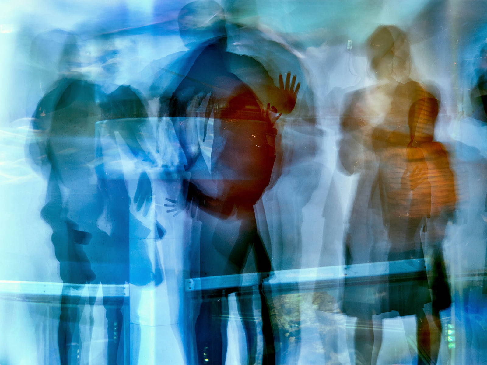 Fine art photography by André Wagner: A raised hand stands out among overlapping blue and orange body forms — X-ray 2, Japan.
